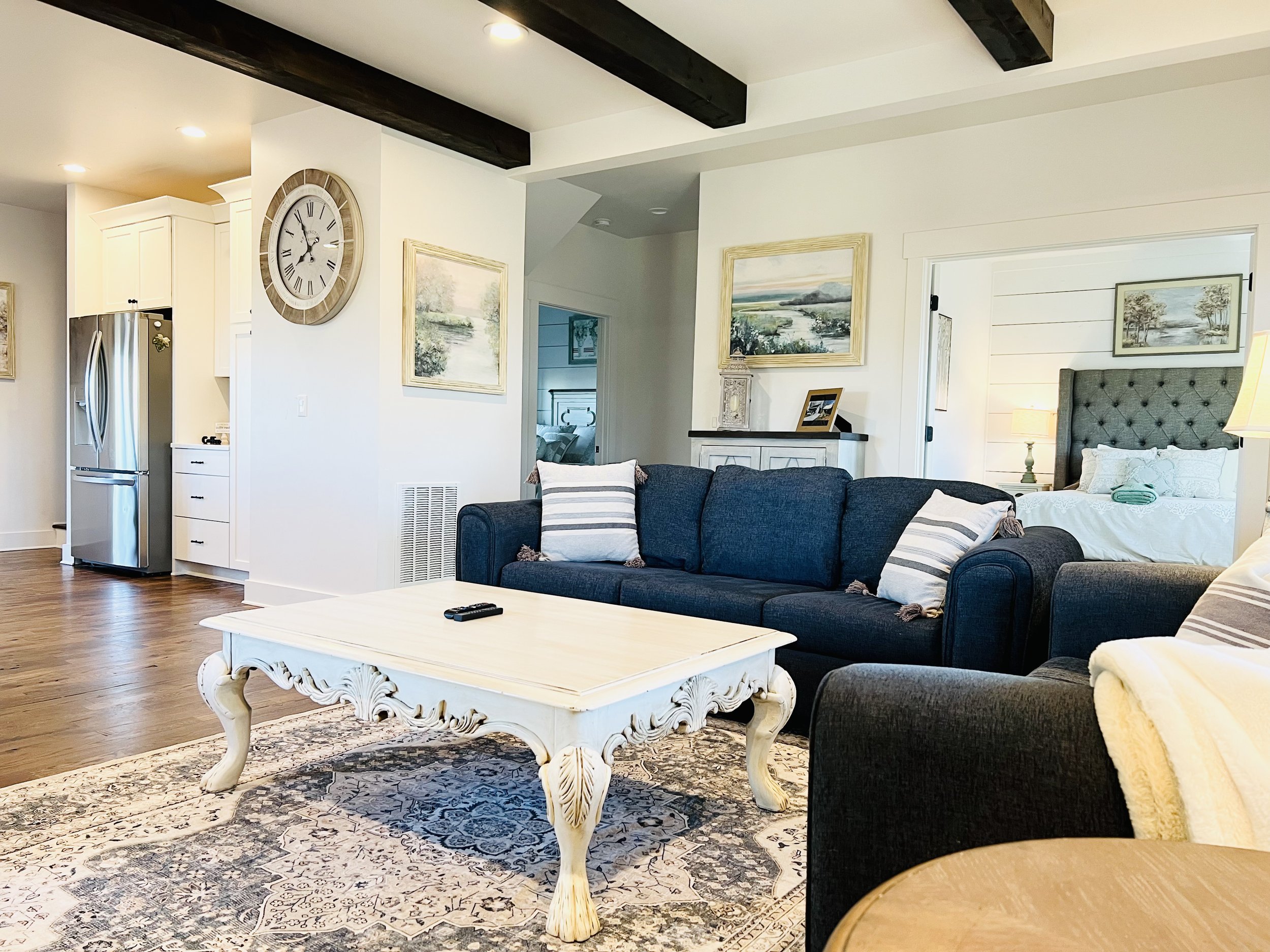 Open-concept living room with French country decor, navy and white seating, elegant sideboard, and large windows, connecting to the kitchen at a Ball Ground, Georgia vacation rental