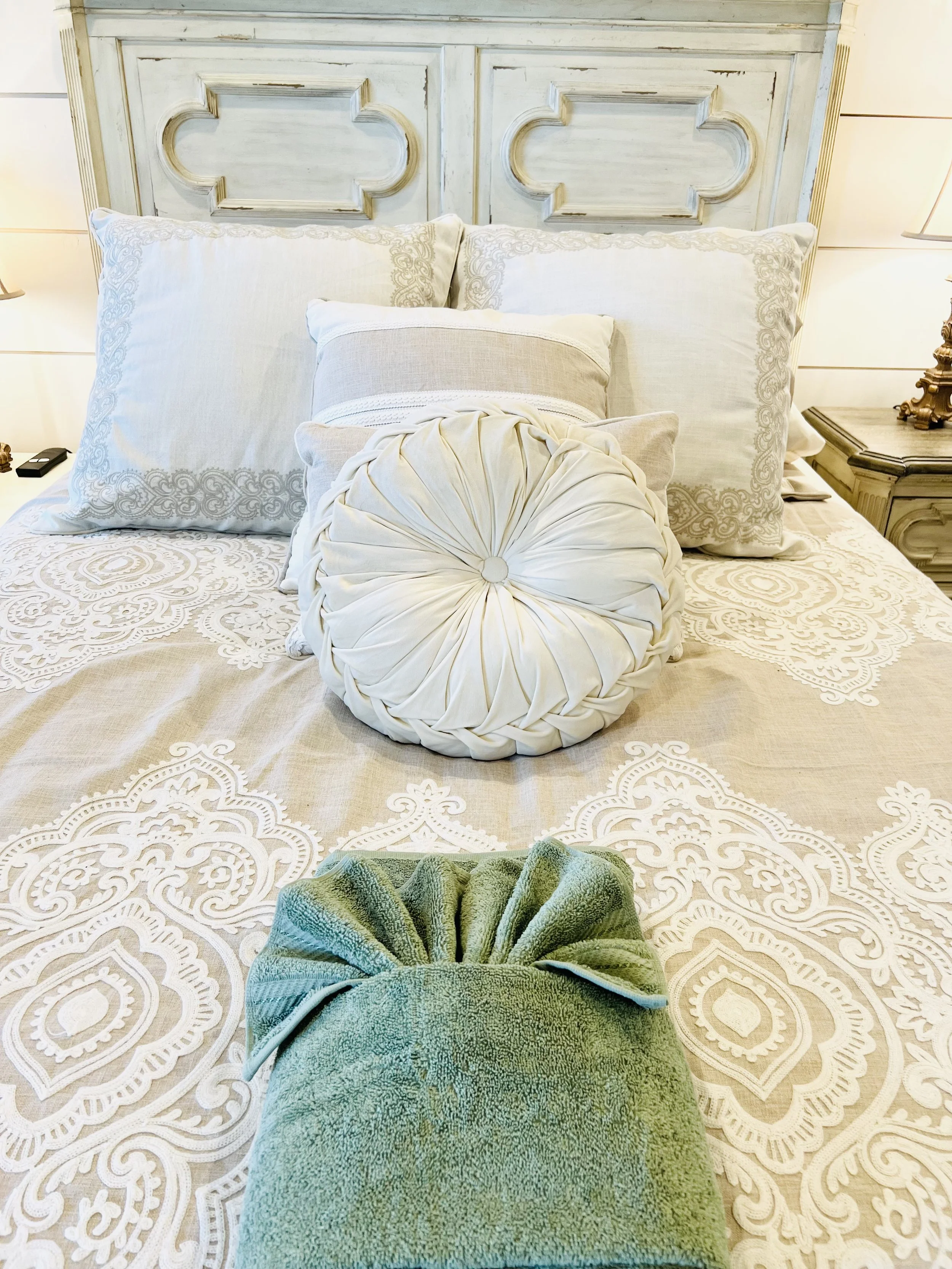 Cozy queen bedroom with a white vintage-style bed, neutral bedding, floral accents, and French country charm in a Ball Ground, GA short-term rental.