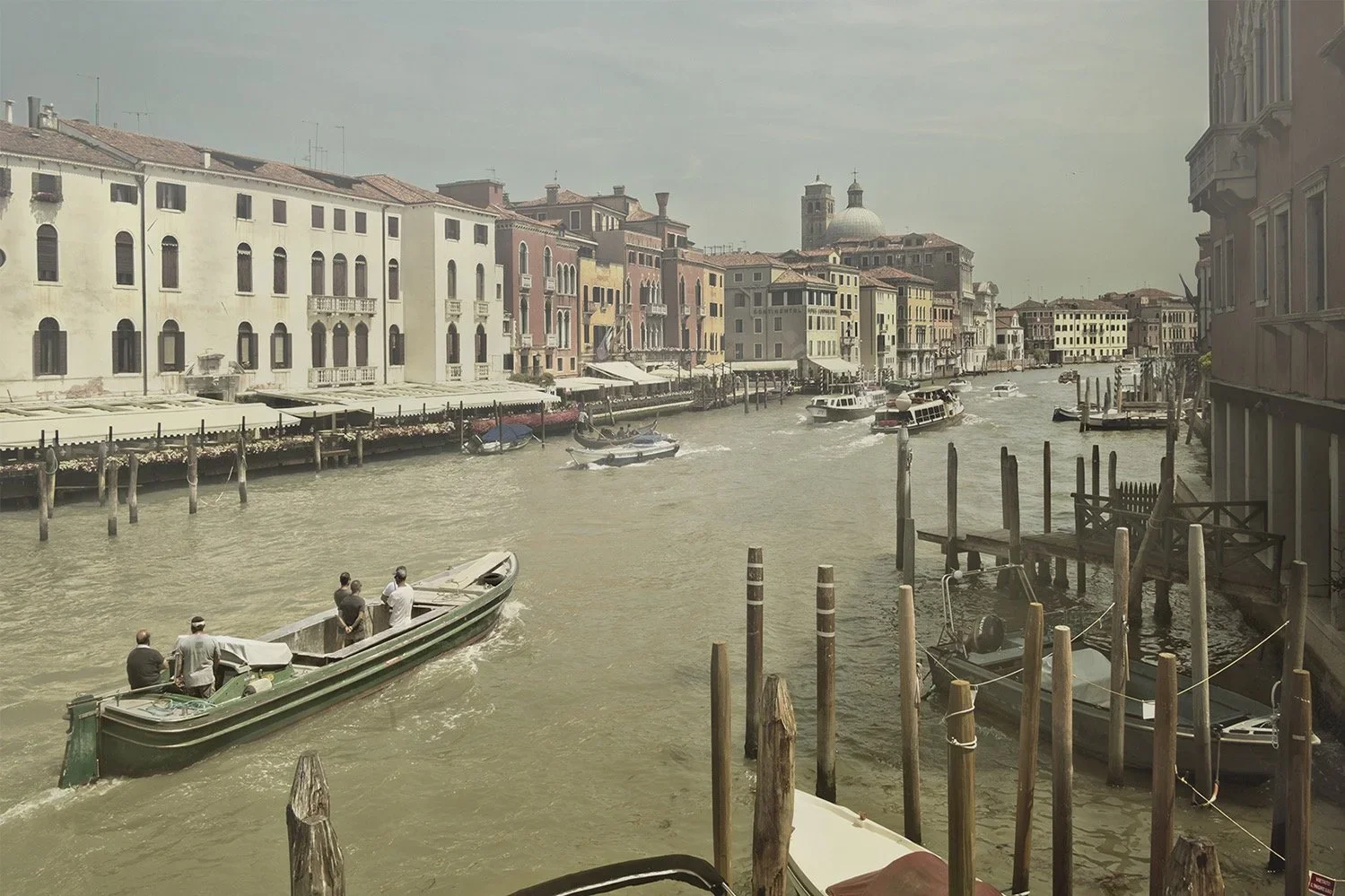View of a canal in Venice, Italy, with several boats and historic buildings along the waterway under a cloudy sky.