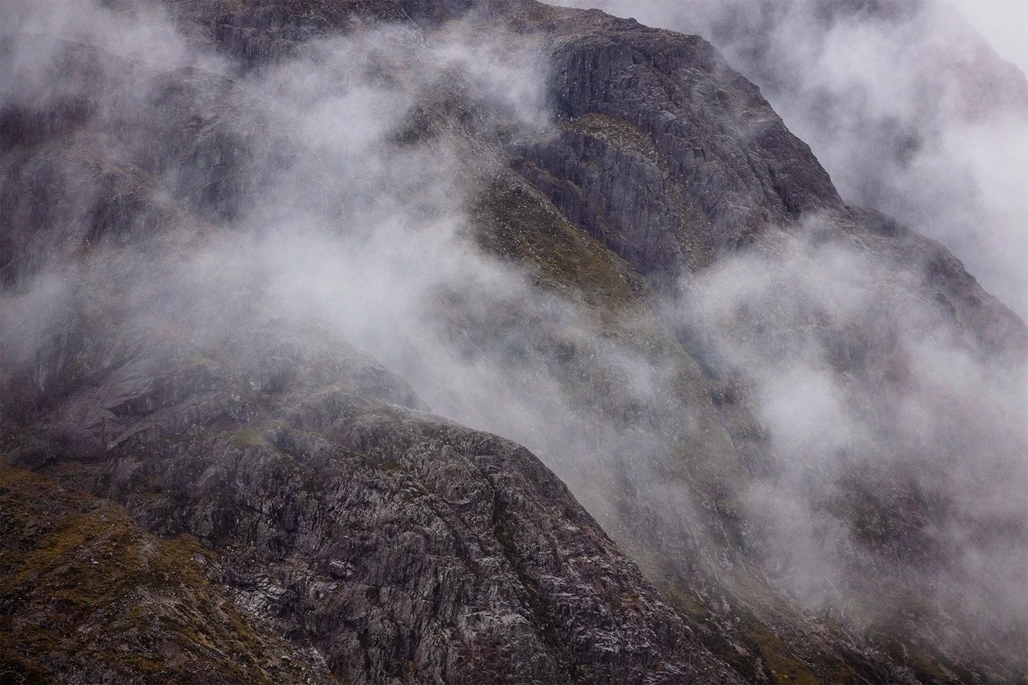 misty mountain peaks with fog rolling over a rugged rocky surface.