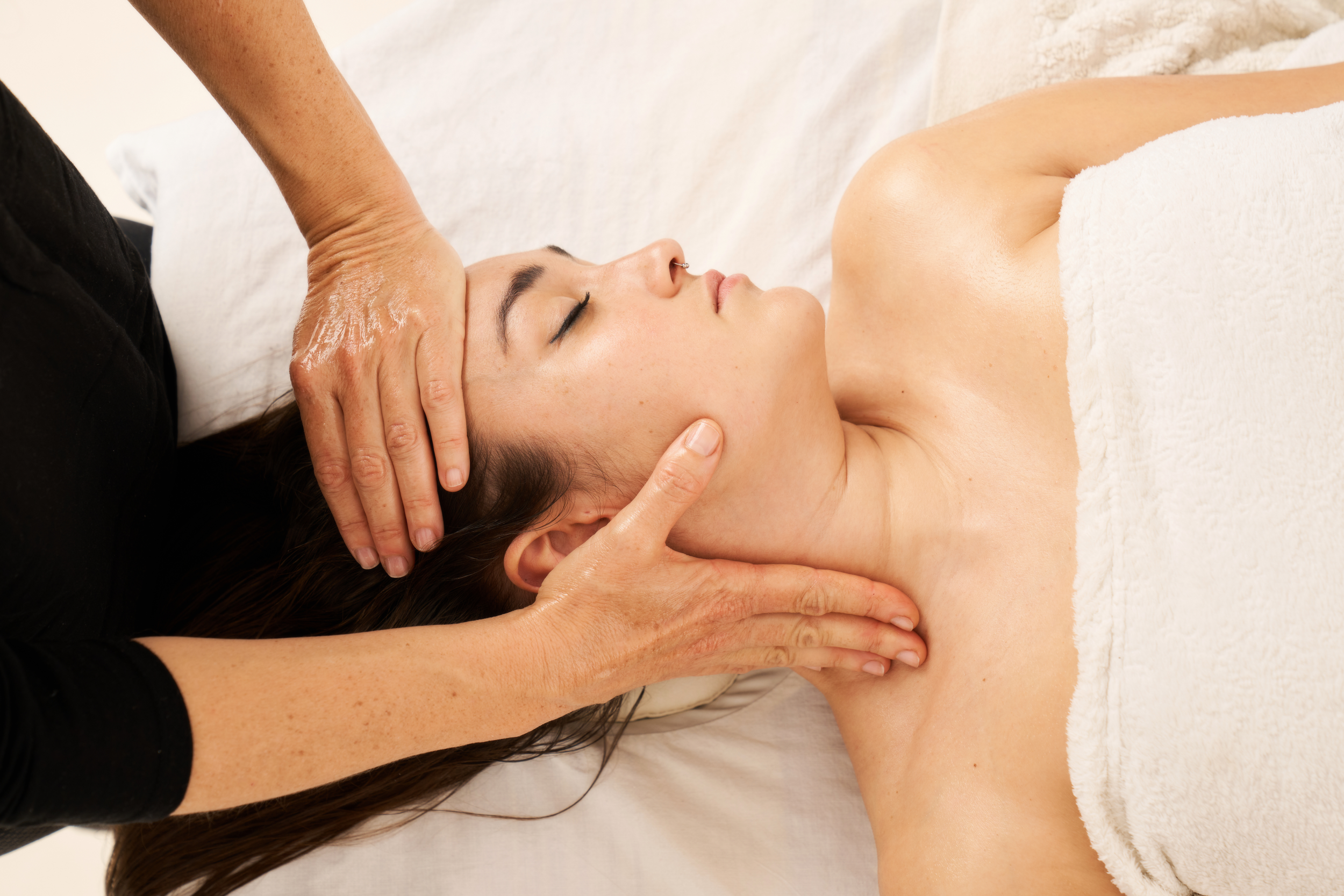 Woman receiving a massage therapy on her neck and shoulders in a spa setting.