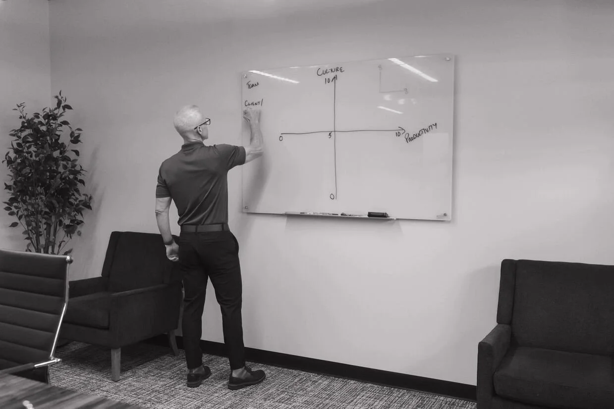 Man writing on white board and teaching business owners how to delegate