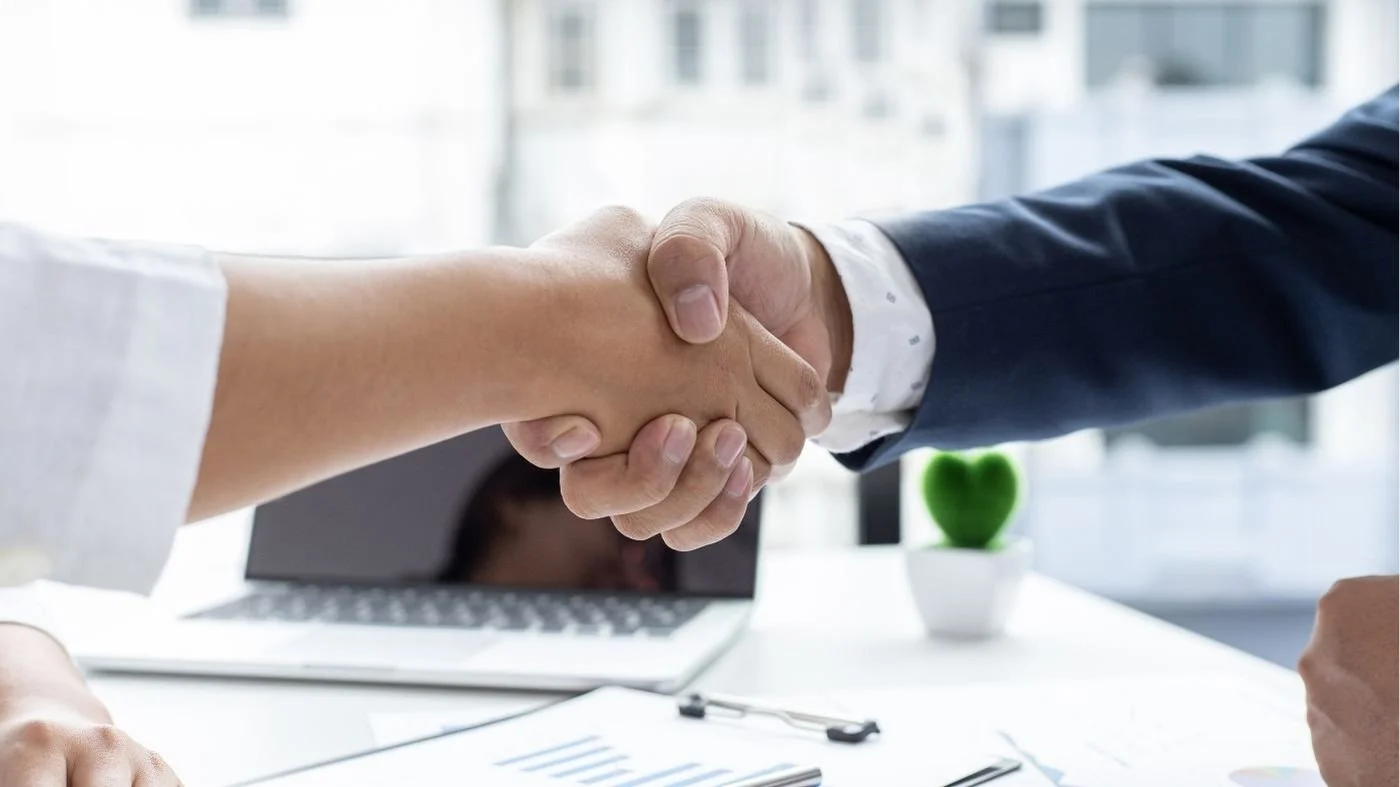 A close up two business professionals shaking hands over an exit strategy agreement.