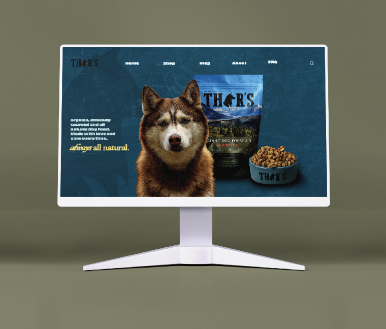 Computer monitor displaying a website for Thar's dog food with an image of a husky dog, dog food bag, and bowl of kibble.
