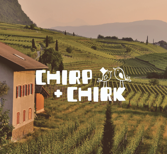 Scenic view of a hillside vineyard at sunset with house in foreground and the words "Chirp + Chirp" with two cartoon birds