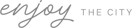 Texto com as palavras 'enjoy the city' em fundo preto, com 'enjoy' em escrita cursiva e 'the city' em fonte sem serifa.