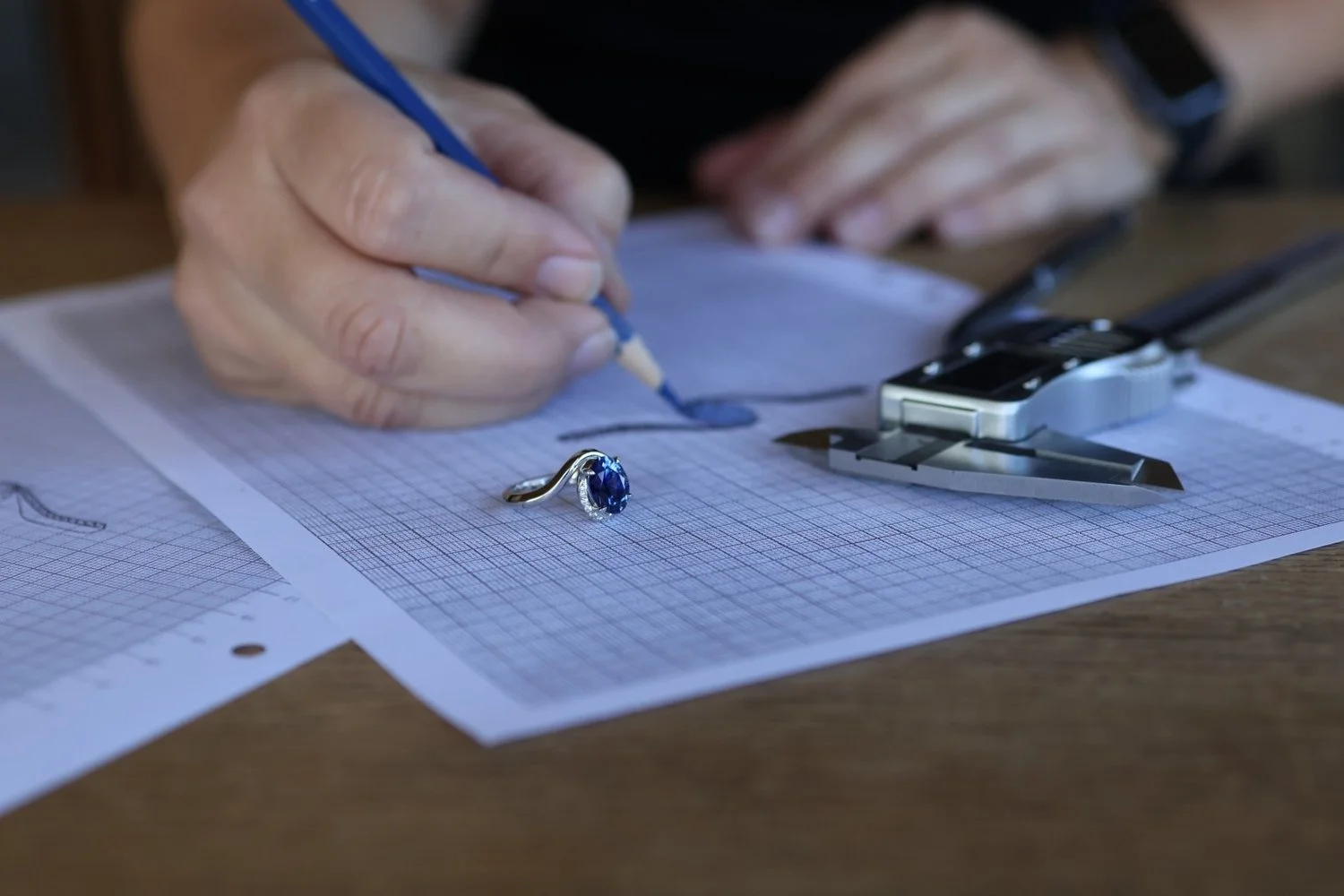 Guldsmed arbetar med en skiss till en specialdesignad ring med blå safir.