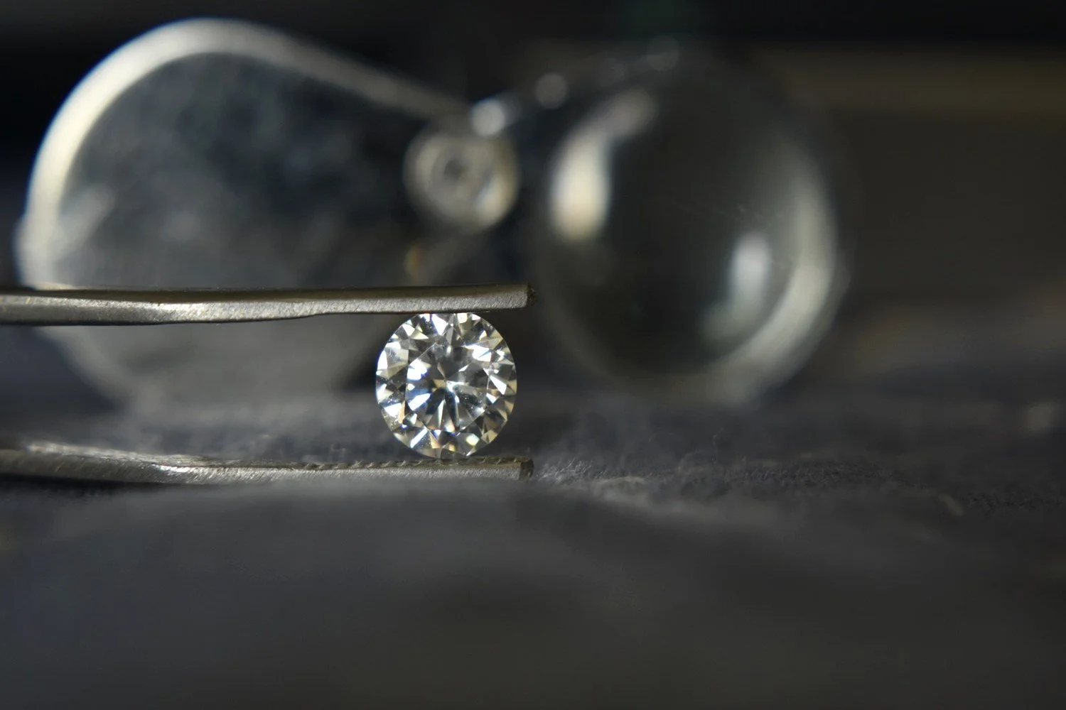 Briljantslipad diamant hållen i pincett vid kontroll i guldsmedsverkstad.