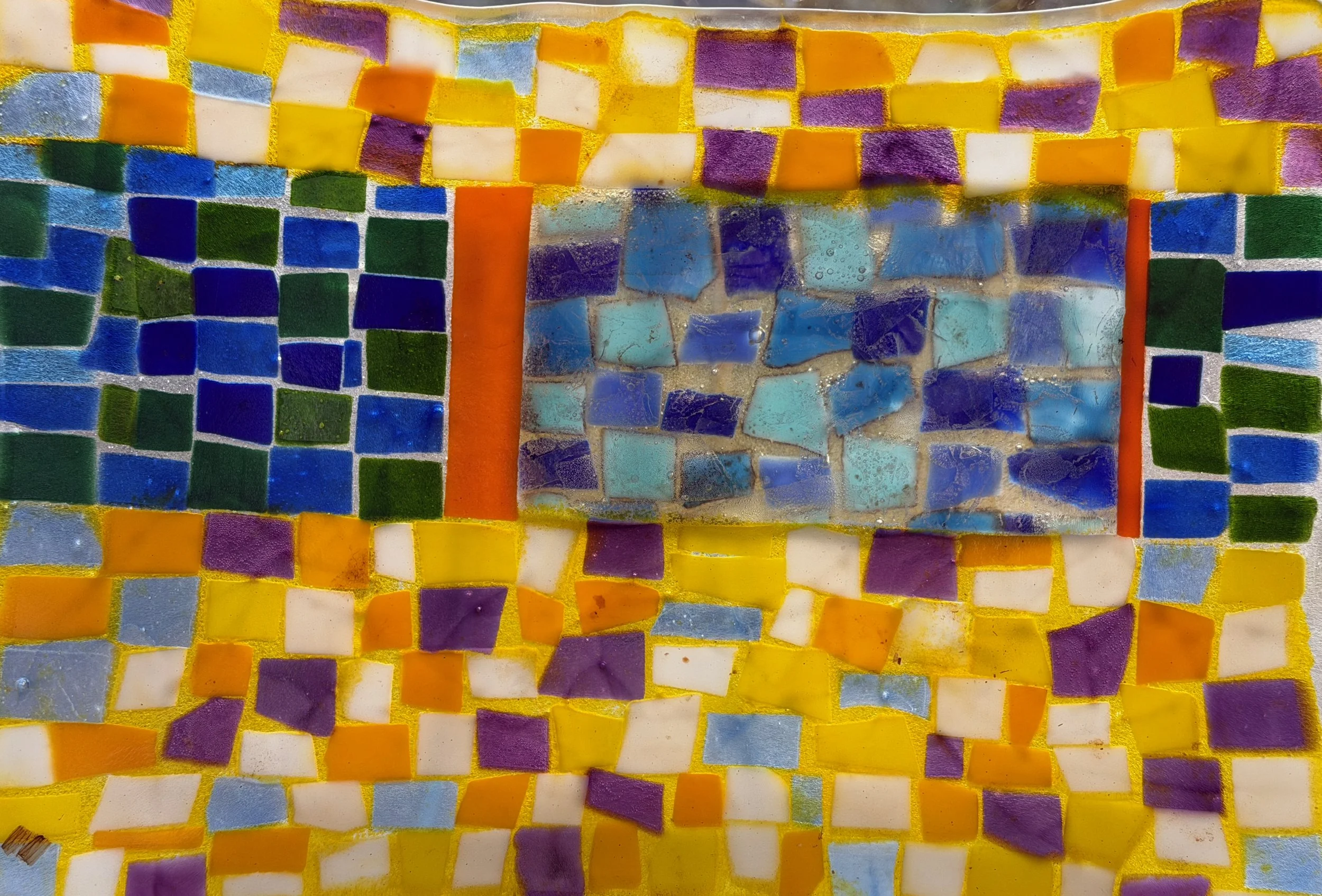 Colorful mosaic made of small glass tiles in various colors including purple, yellow, blue, green, white, and orange.