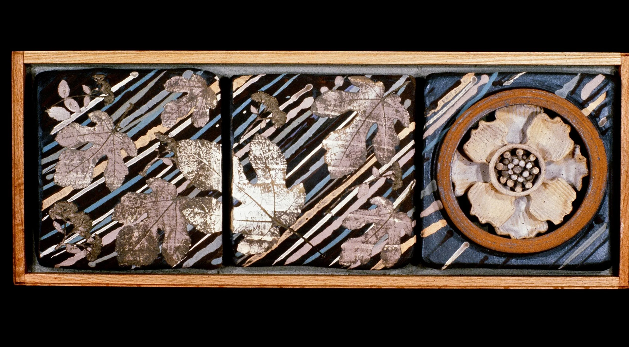 Decorative wooden box with three compartments, featuring dried botanical leaves on dark, striped background, and a central flower-like design with shell motifs.