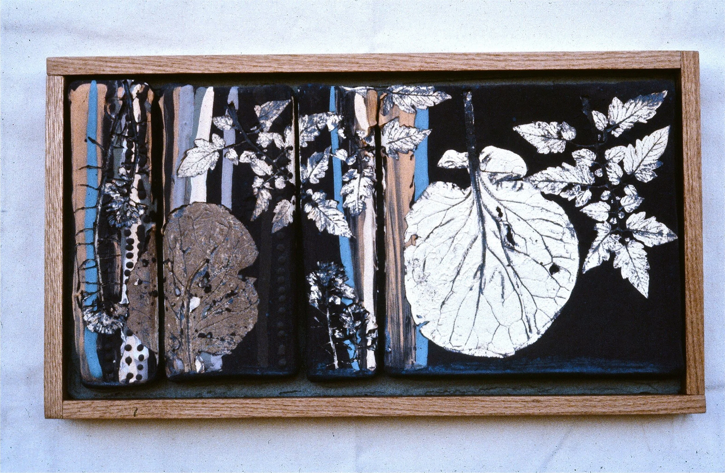 Mixed media artwork with painted and collaged leaves and patterns in a wooden frame.