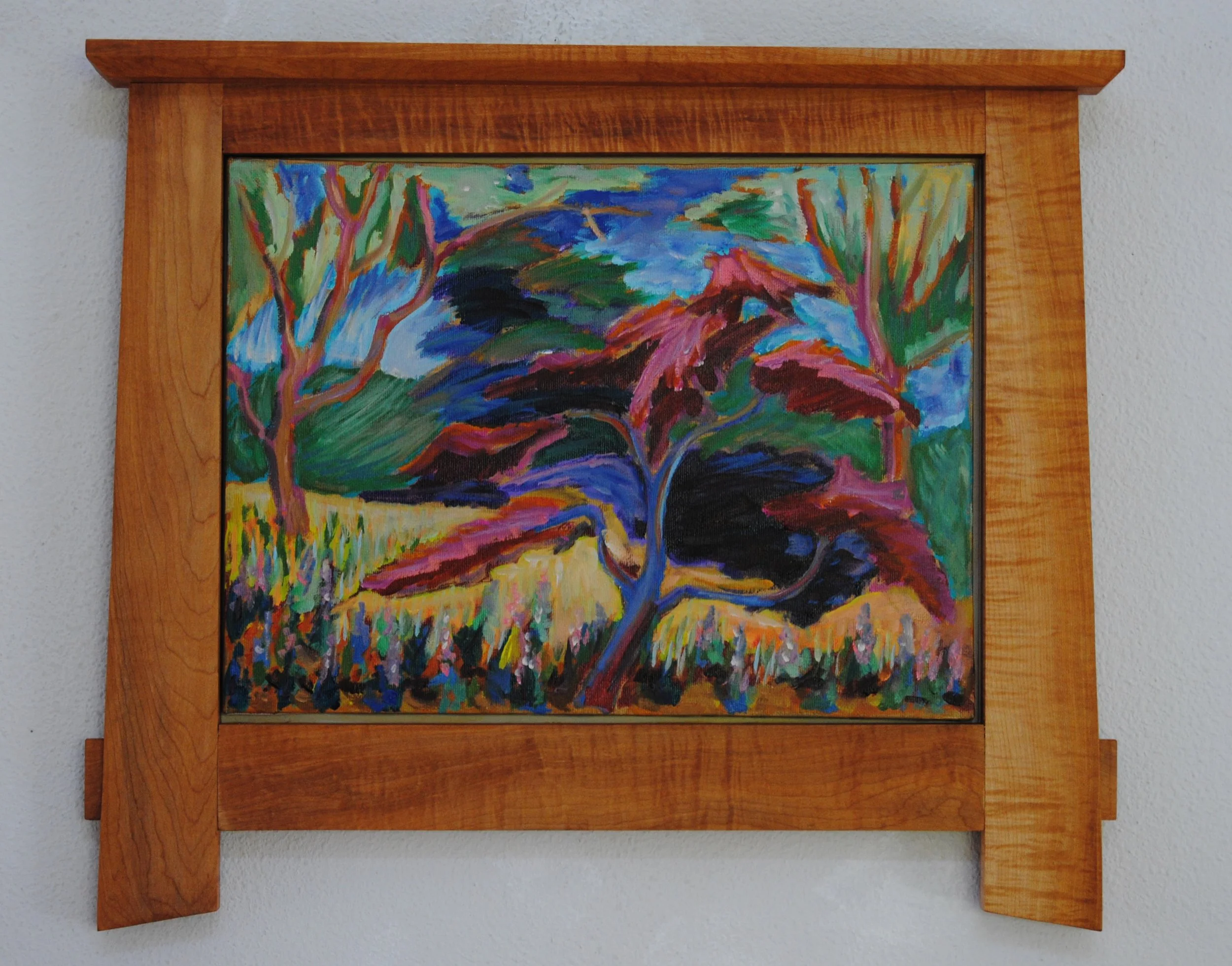 Colorful landscape painting of trees and a field framed in wood.