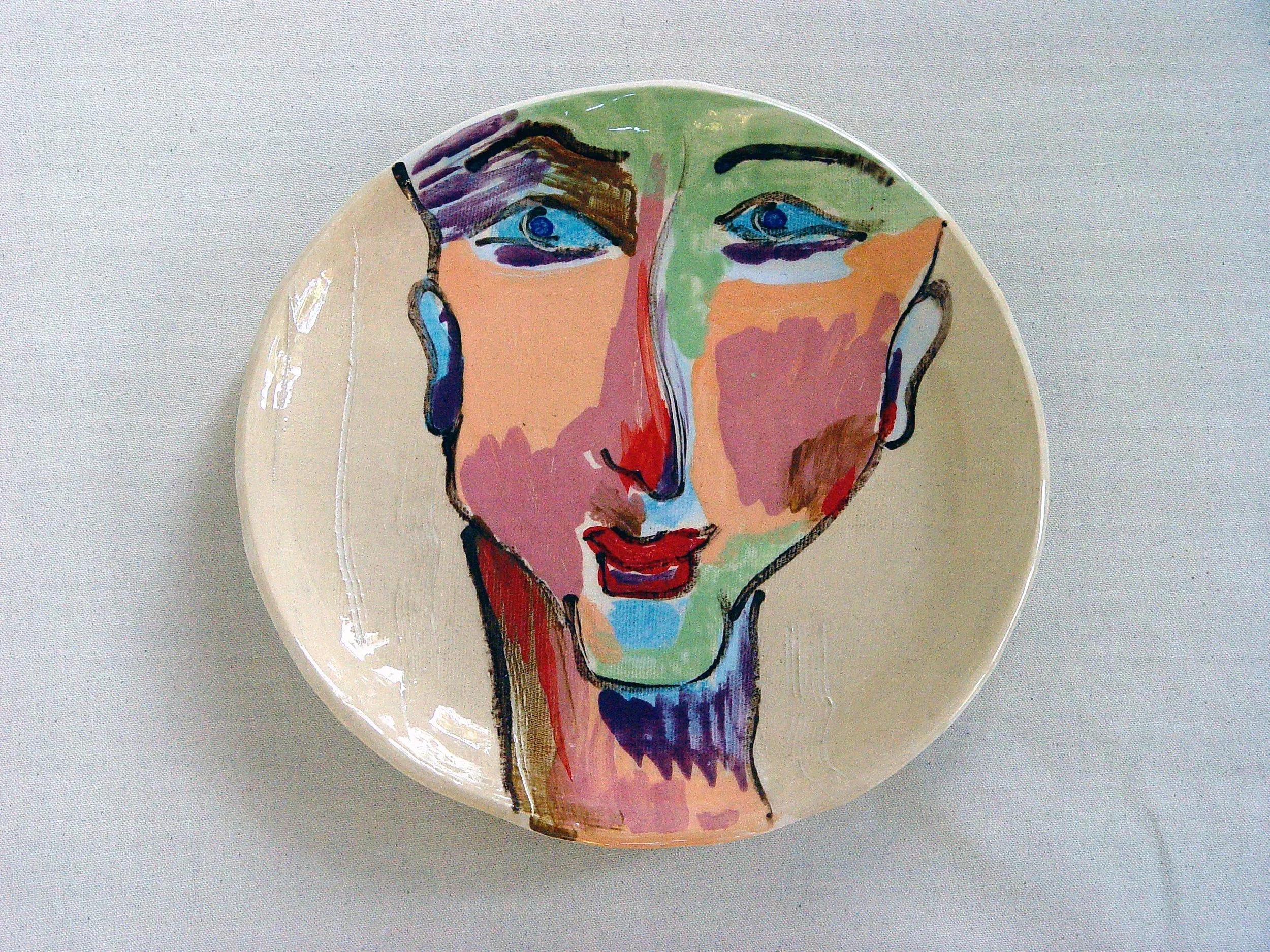 Decorative plate featuring a colorful abstract portrait of a woman's face with exaggerated features and bold brushstrokes.