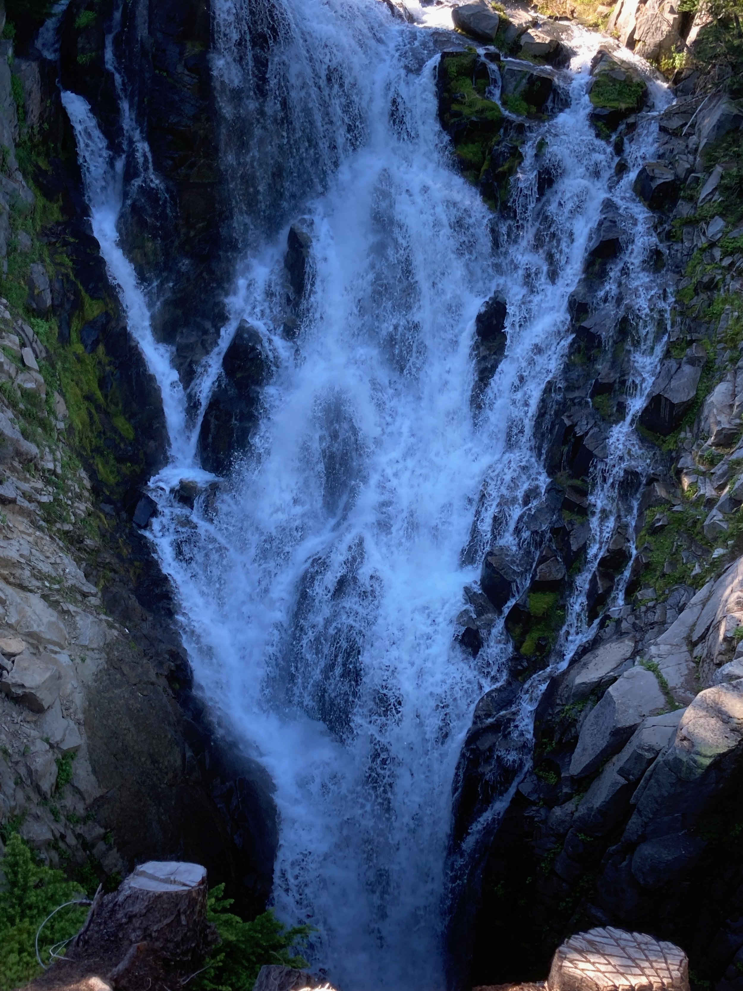 A tall waterfall cascading down a rocky cliff surrounded by greenery.
