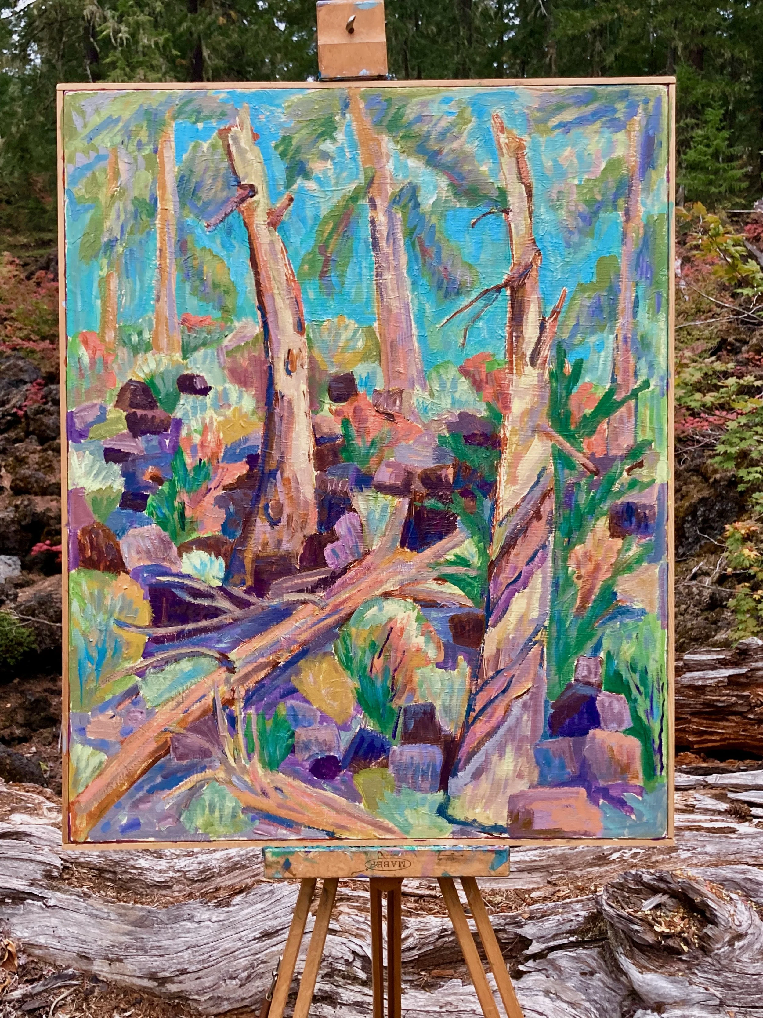 A colorful landscape painting of a forest with trees, rocks, and plants, created with bold brush strokes and vibrant colors, displayed on an easel outdoors.