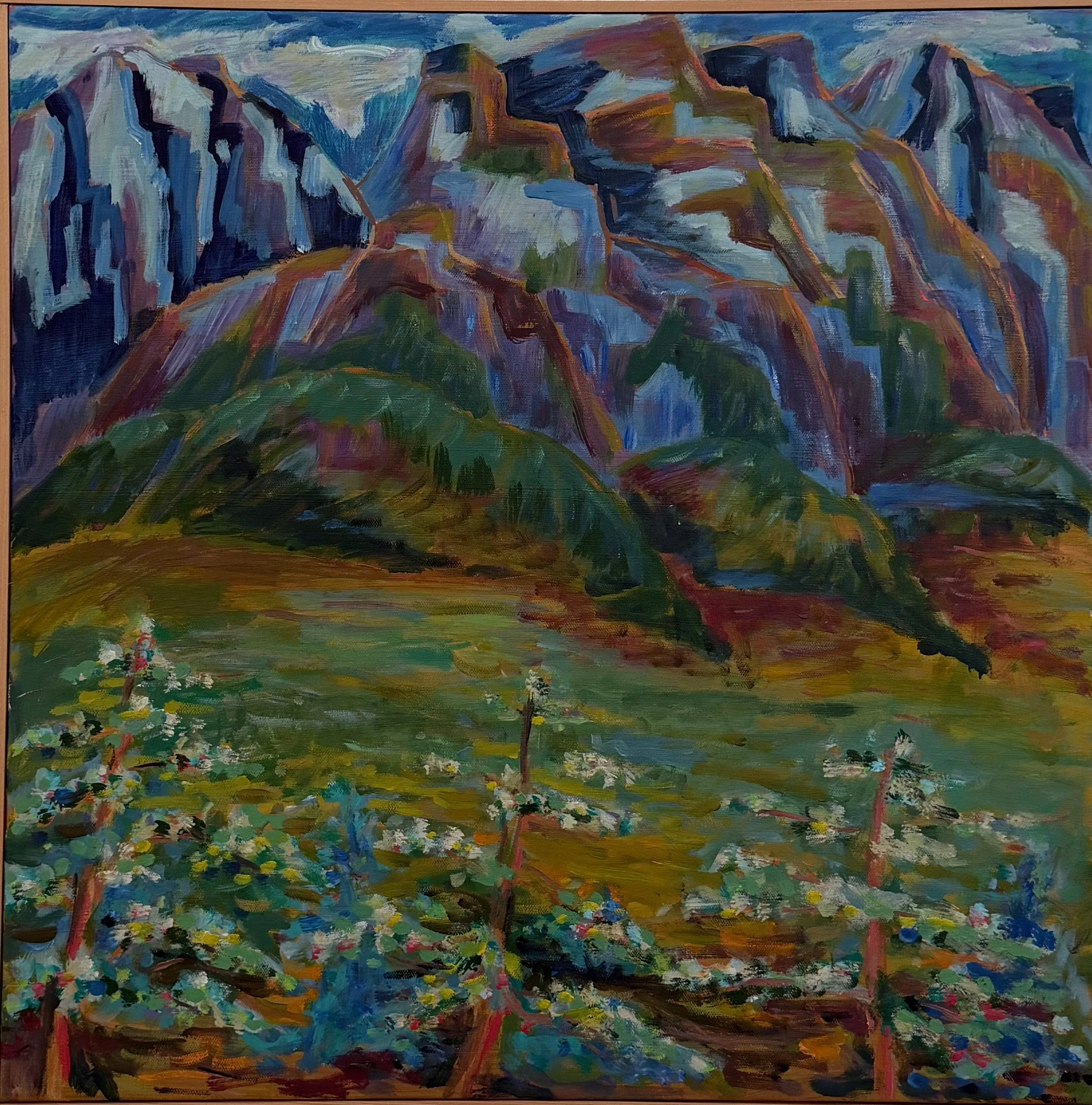 An oil painting of mountains with colorful, layered peaks and a green foreground with flowering plants and small trees.