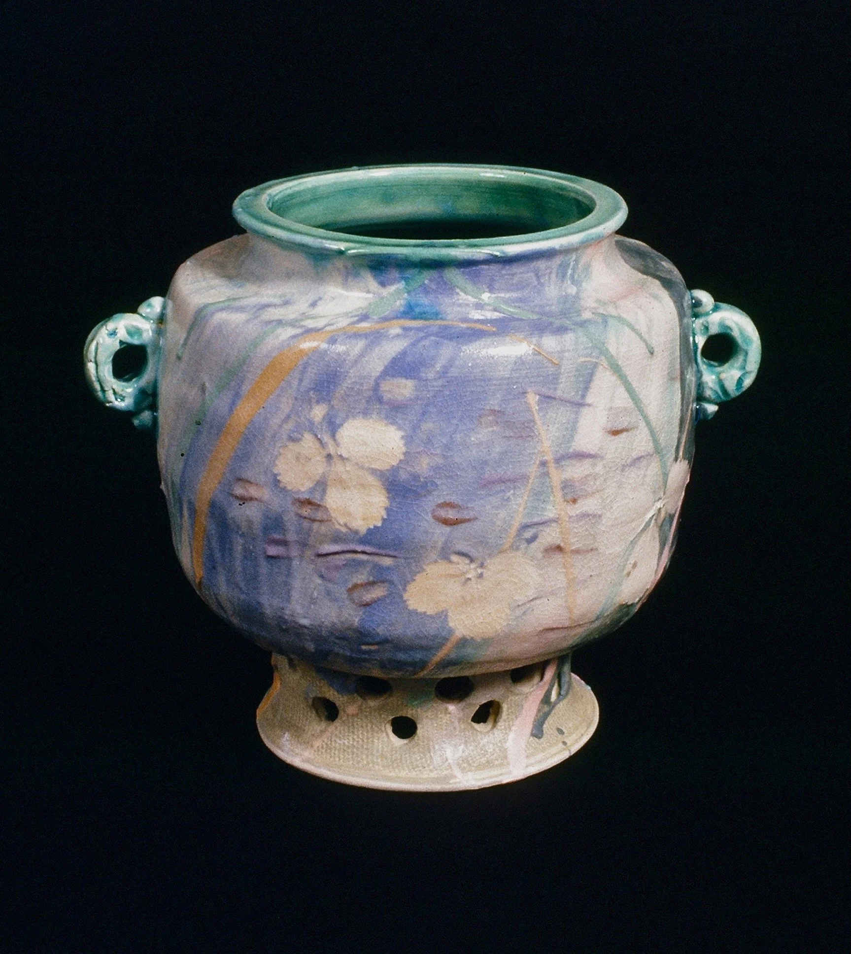 Ceramic vessel with floral and abstract patterns on a black background.
