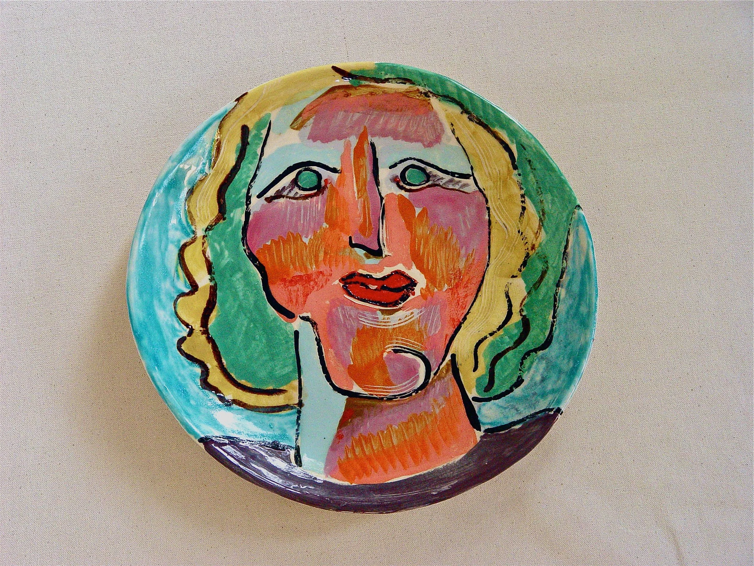 Colorful artistic portrait of a person's face painted on a round surface with bold brushstrokes and vibrant colors.