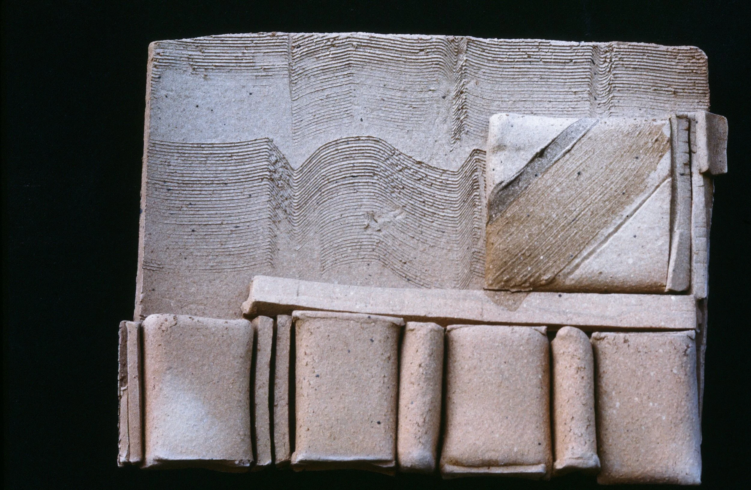 Ancient clay tablet with cuneiform writing and carved geometric patterns.