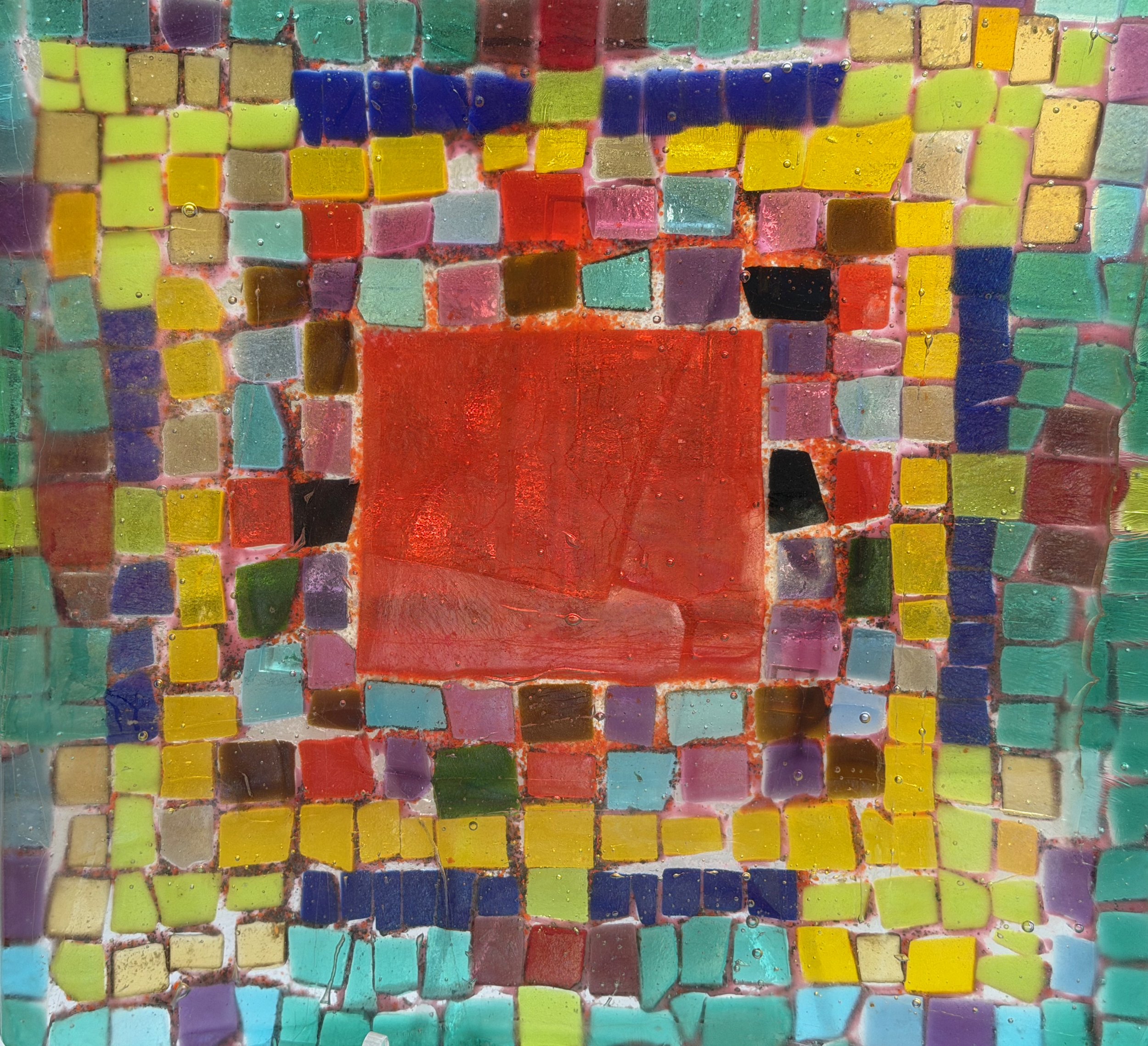 A colorful mosaic composed of small square glass tiles in various colors, with a large red square tile in the center and a border of yellow, purple, blue, green, and pink tiles.