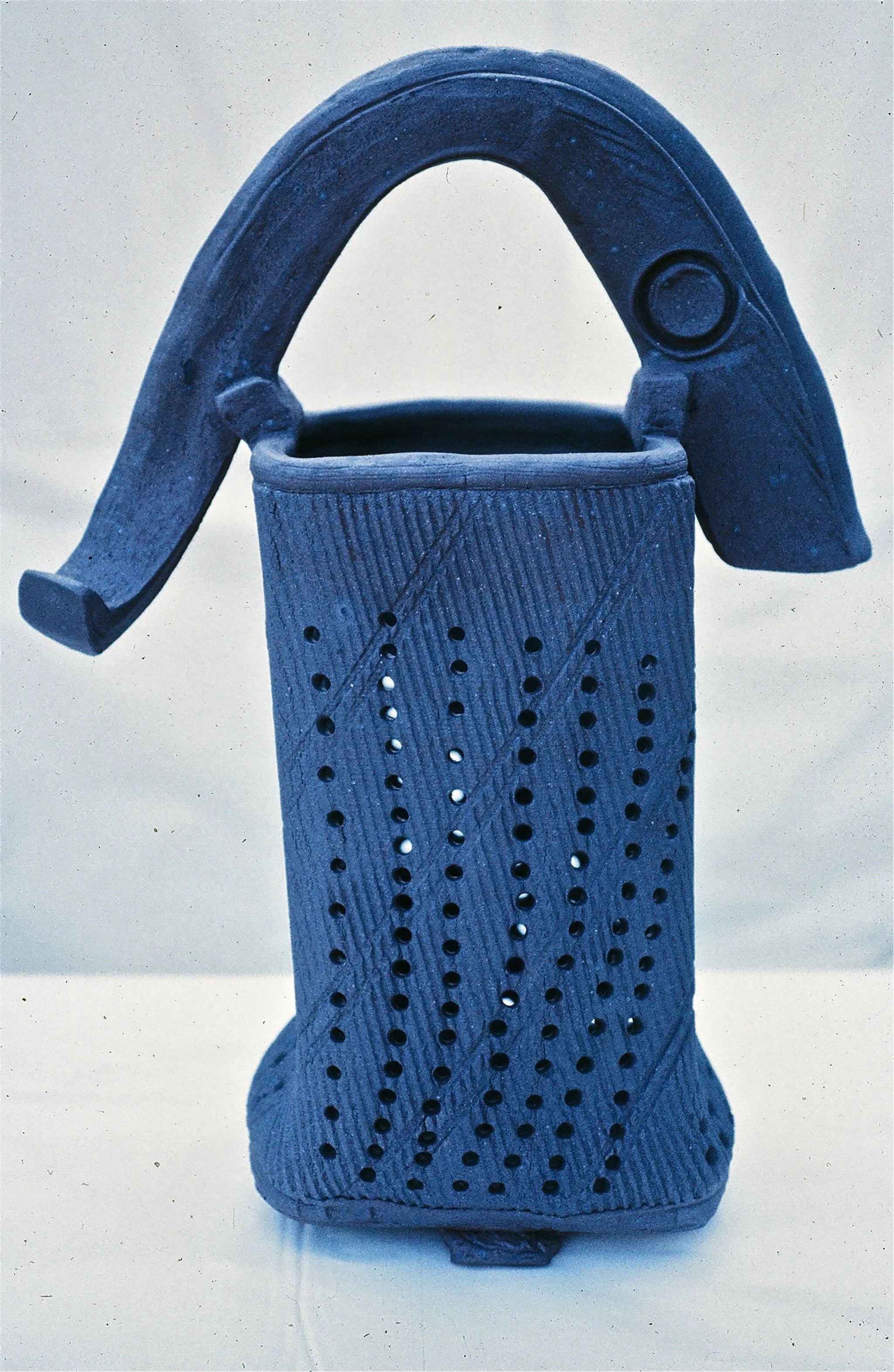 A vintage metal perforated lantern with a curved handle on top.