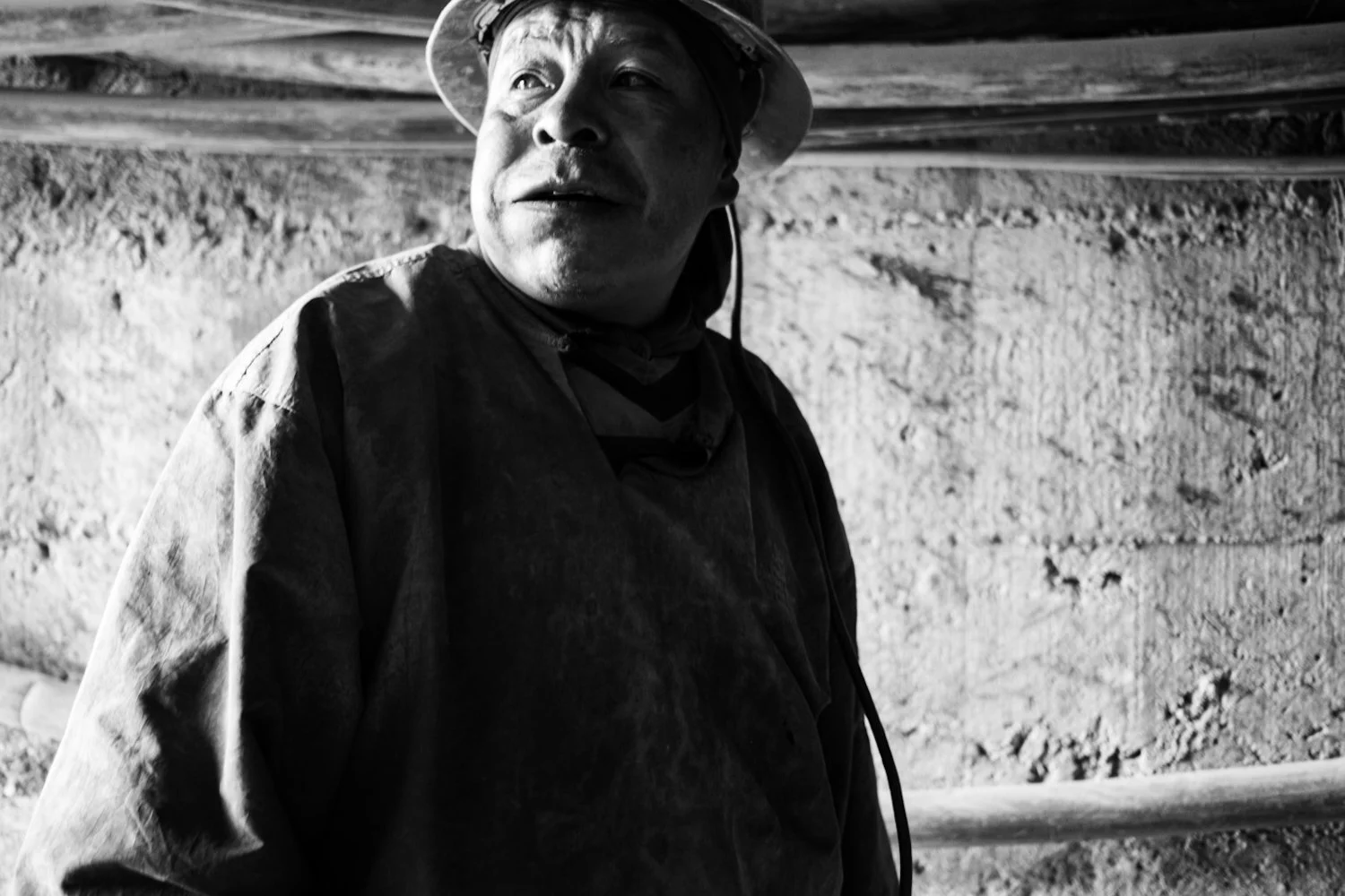 A man wearing a helmet and work clothes looks up in an underground construction site.