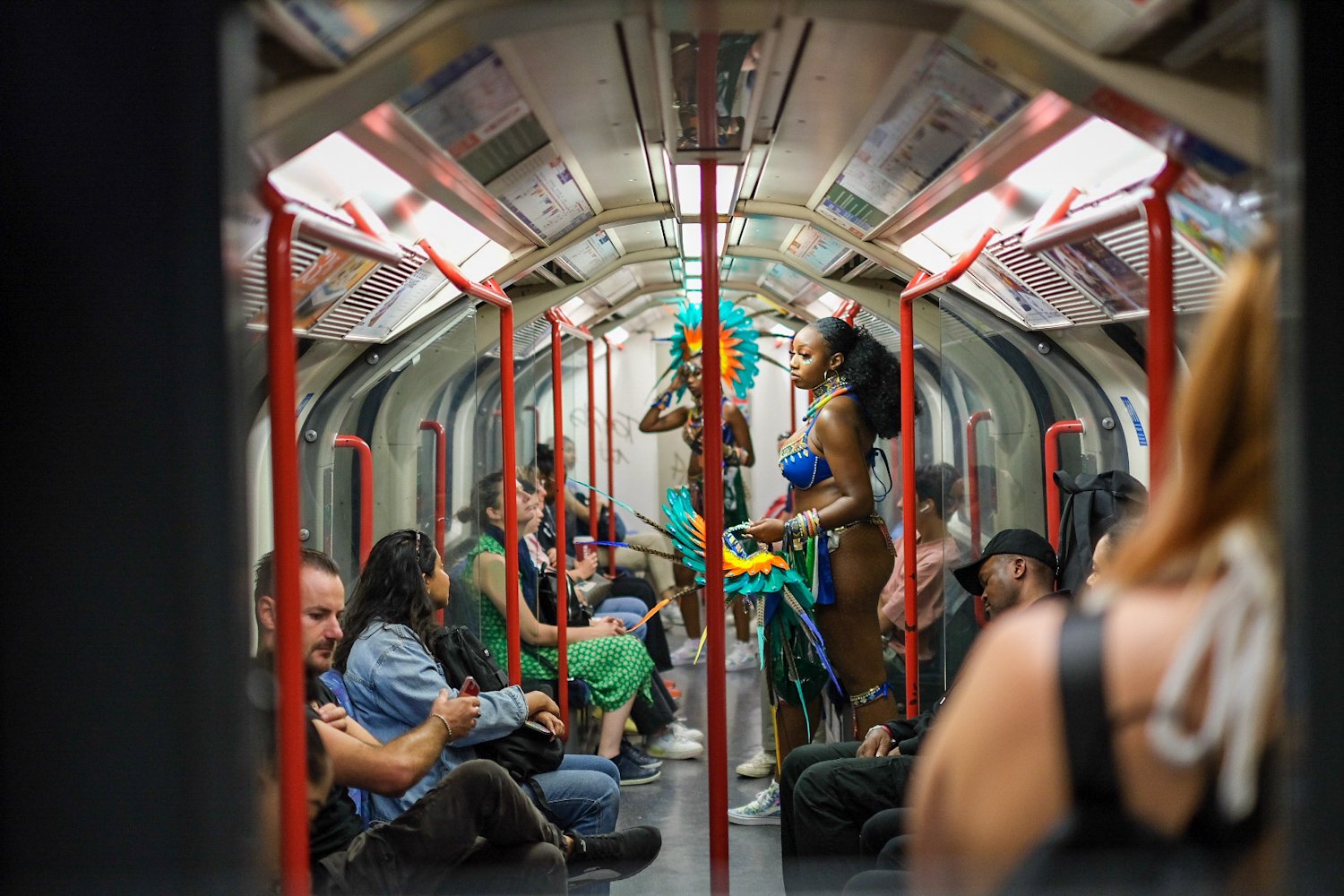 People riding the subway with performers in colorful costumes performing in the aisle.