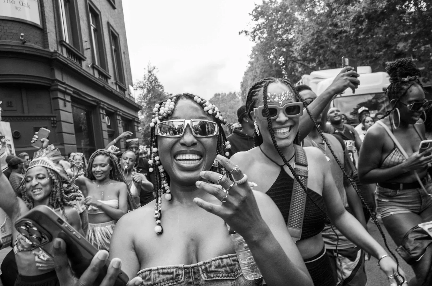 Group of women smiling, taking photos, and celebrating during a parade or outdoor event
