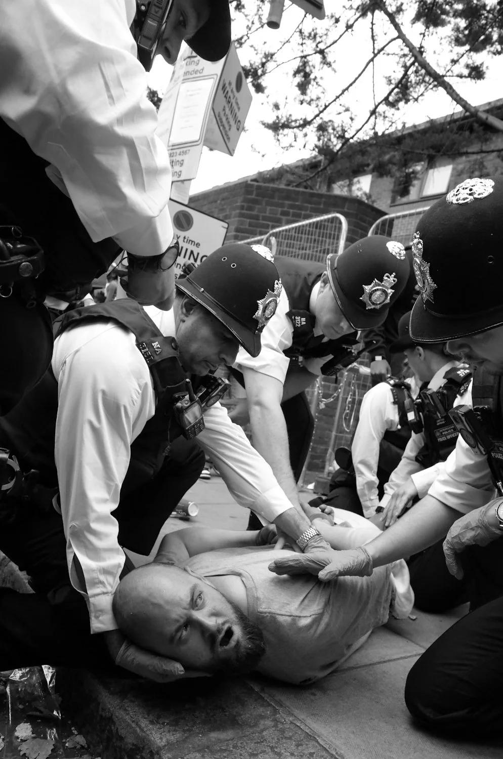 Police officers arrest a man lying on the ground during a protest or demonstration.