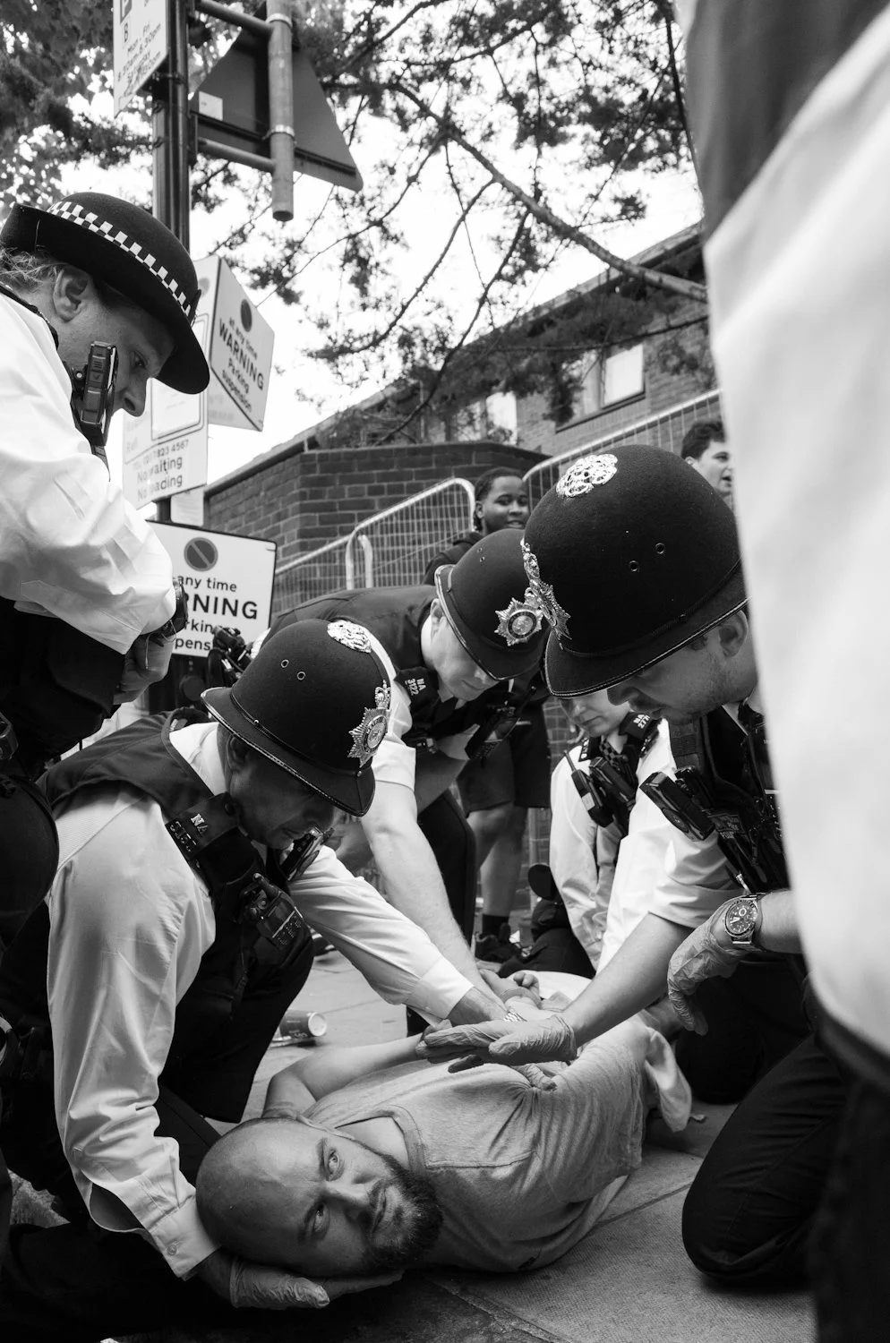 Police officers in uniform assisting a man lying on the sidewalk during an emergency.