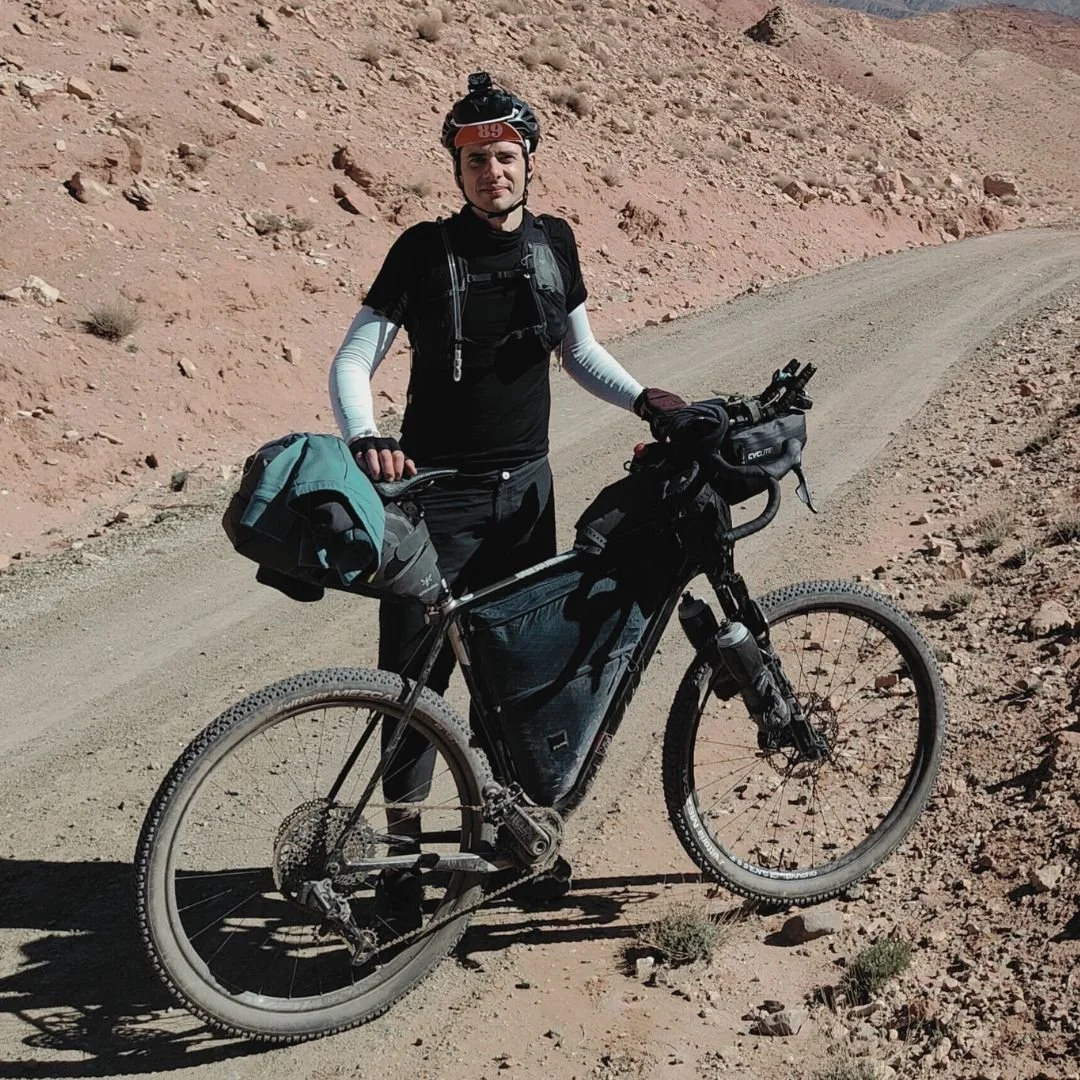 Hombre con casco y ropa deportiva en bicicleta de montaña en un camino de tierra en un paisaje árido y rocoso
