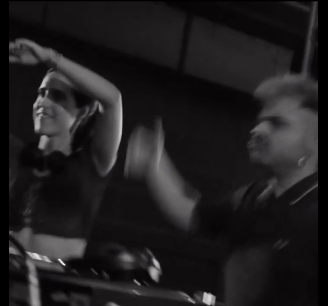 Dos personas bailando y disfrutando en un ambiente oscuro, parece ser un evento o fiesta.