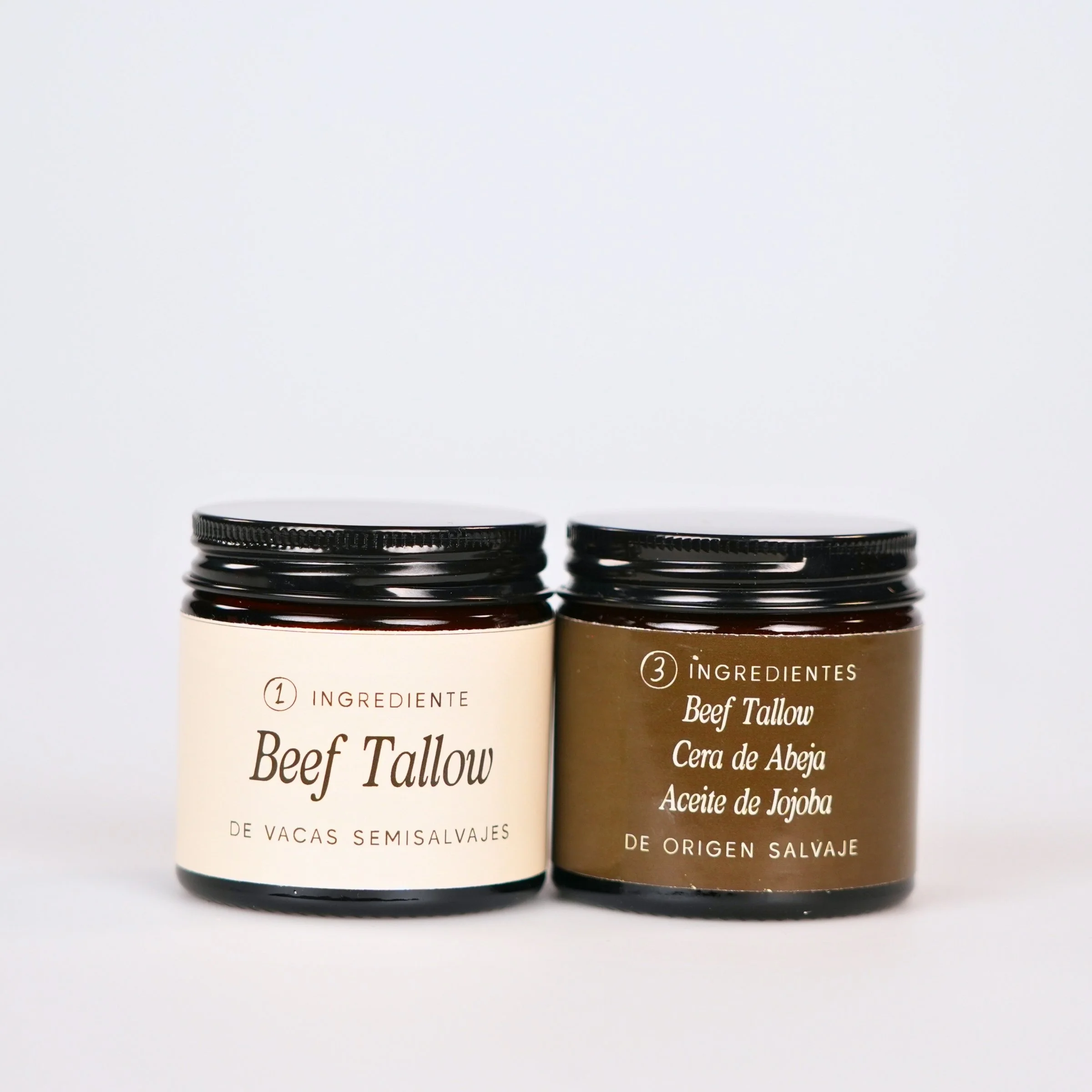 Dos frascos con etiquetas que indican ingredientes para productos naturales, uno con cárnicas y otro con ingredientes adicionales como cera de abeja, aceite de jojoba y carne de vaca.