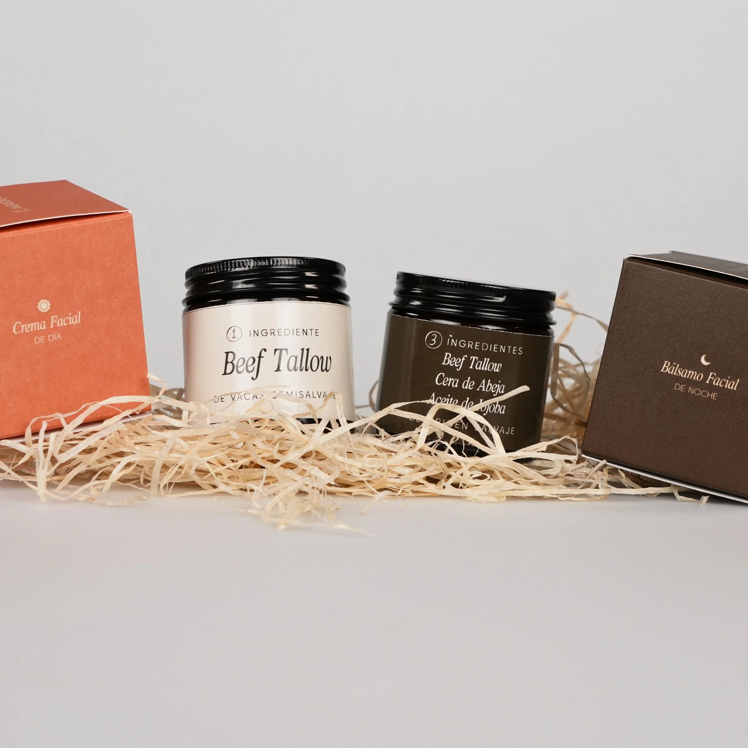 Conjunto de productos de cuidado facial, incluyendo cremas y bálsamos, con empaques en tonos terracota y marrón, colocados sobre papel de esparto.