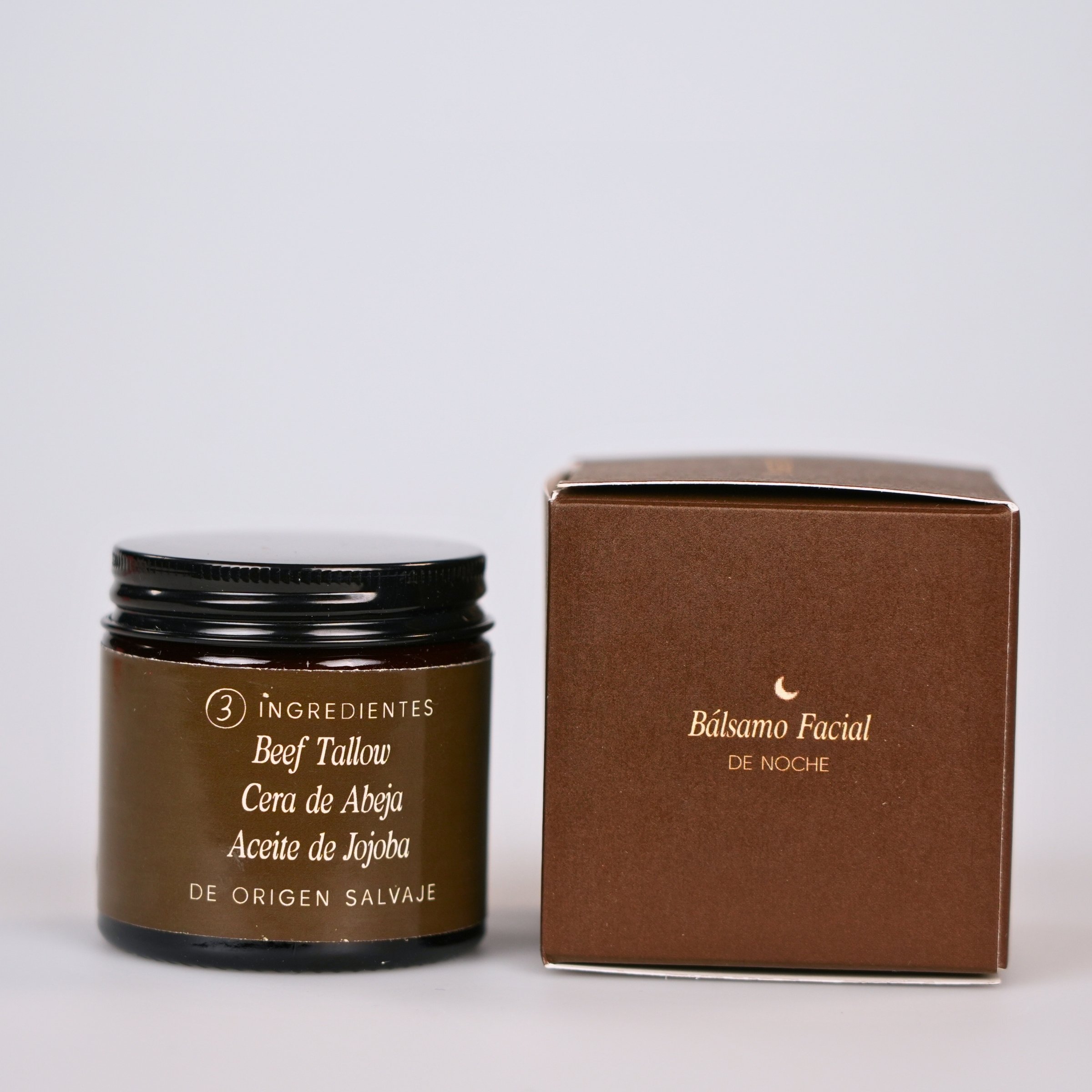 Producto de cuidado facial con ingredientes naturales, envuelto en envase marrón y caja de color marrón, fondo gris claro.