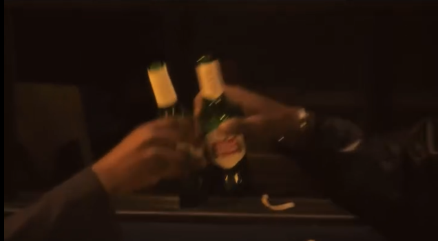 Personas brindando con botellas de cerveza en un entorno oscuro.