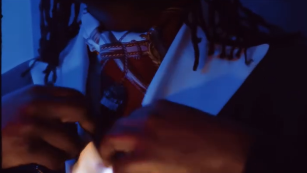 Persona con cadenas y ropa de estilo tradicional, en un entorno oscuro y con iluminación azul.