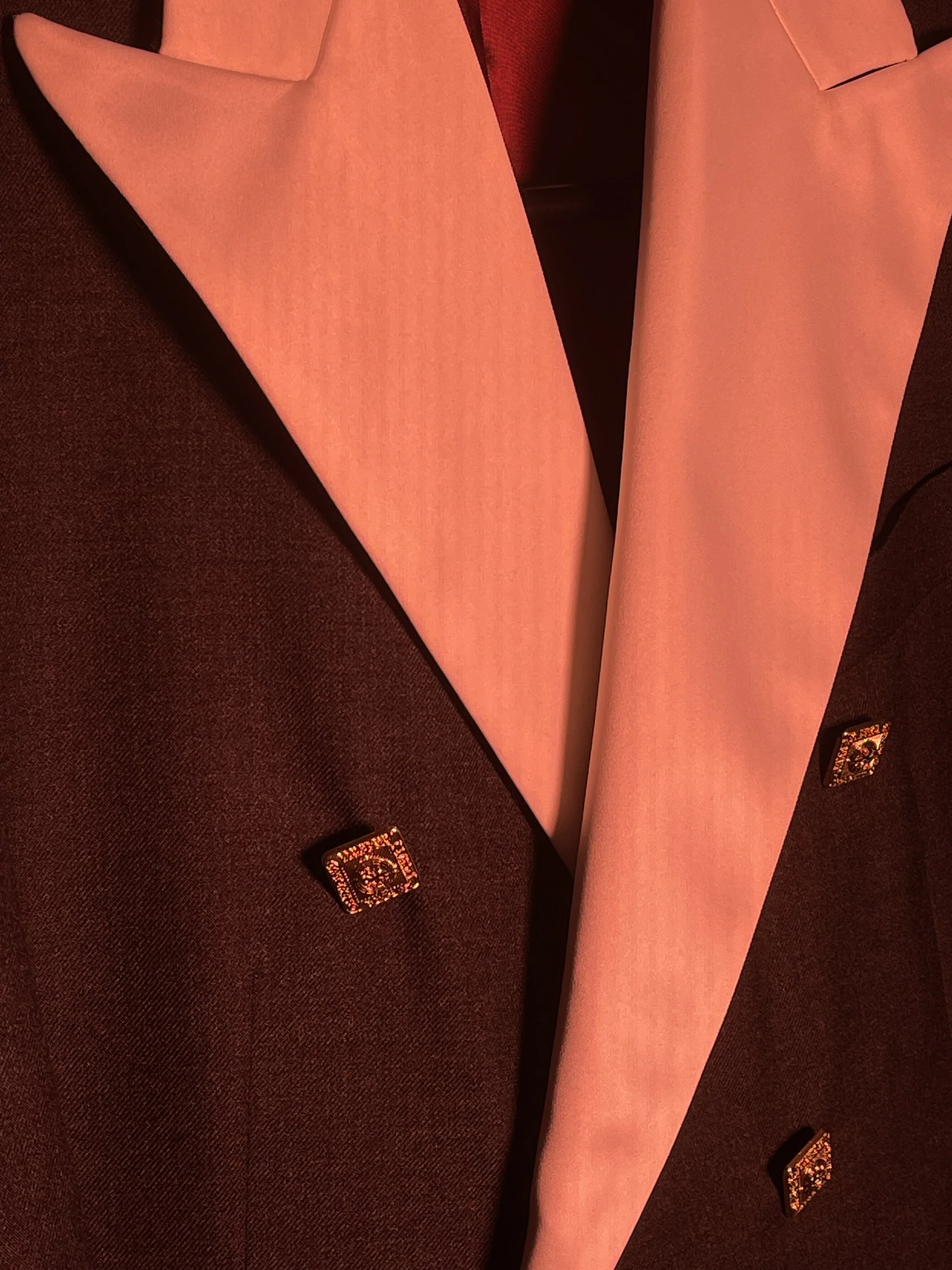 Faje de color rosa sobre sillon de color marrón oscuro con botones decorativos.