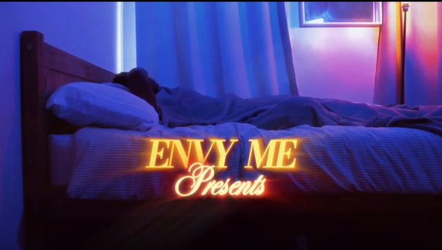 Texto en la imagen que dice 'ENVY ME Presents' con fondo de una habitación con cama y cortinas moradas, iluminada con luz azul y rosa.