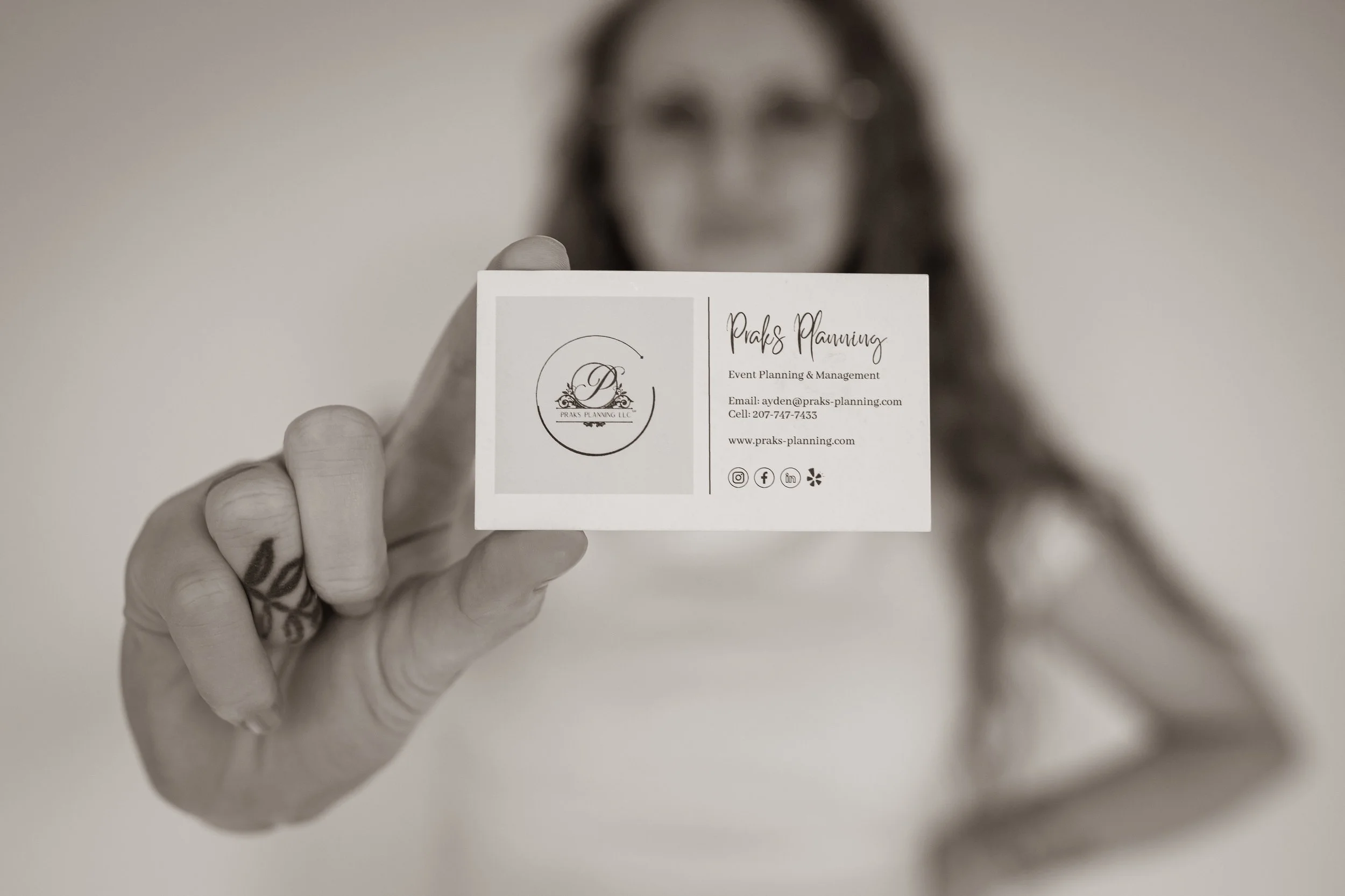 Person holding a business card for Praks Planning LLC, with the focus on the card and the person slightly blurred in the background.