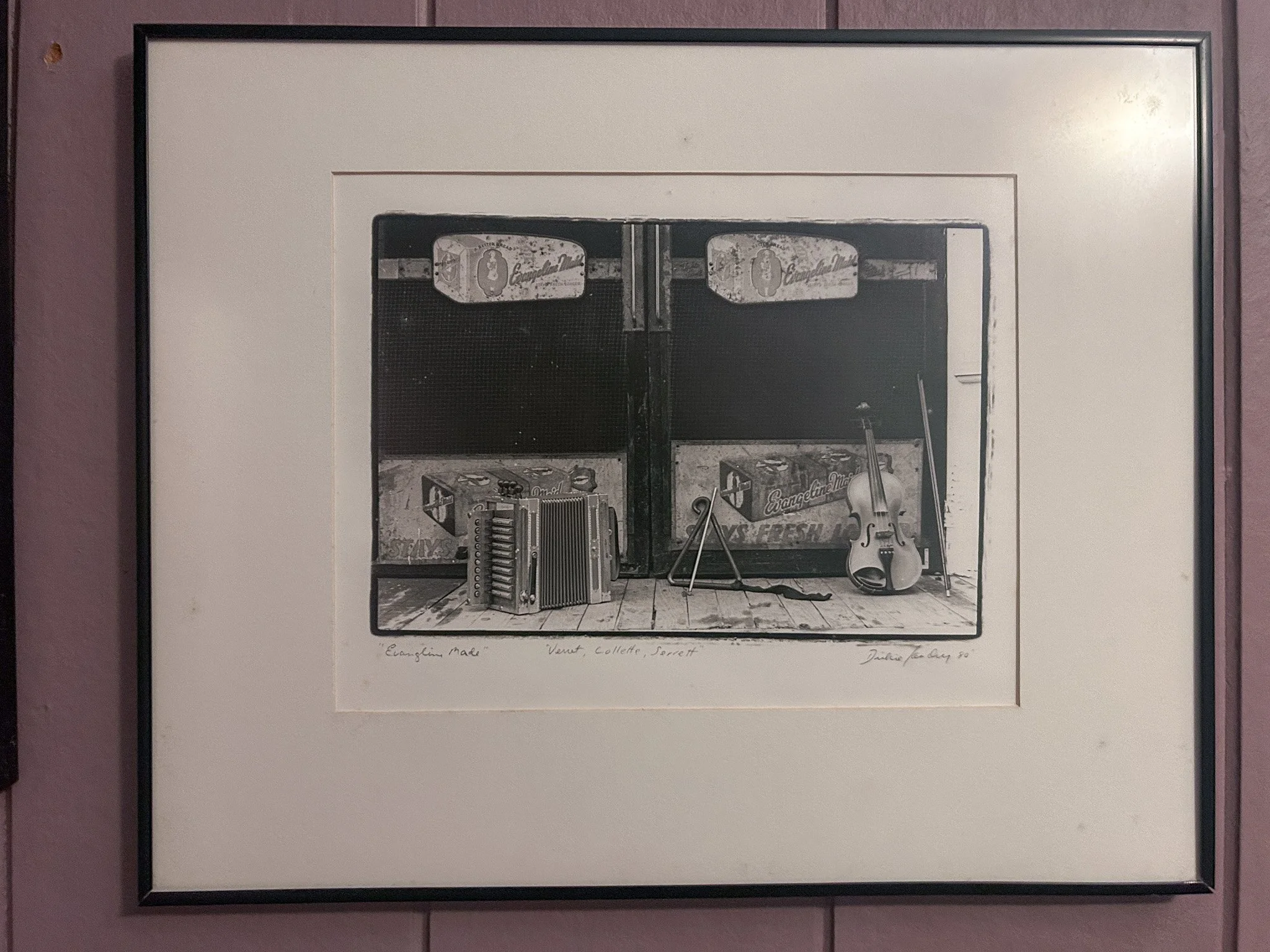 Black and white art print of a vintage scene showing a corrugated metal door with music equipment and a violin leaning against the wall on a wooden floor