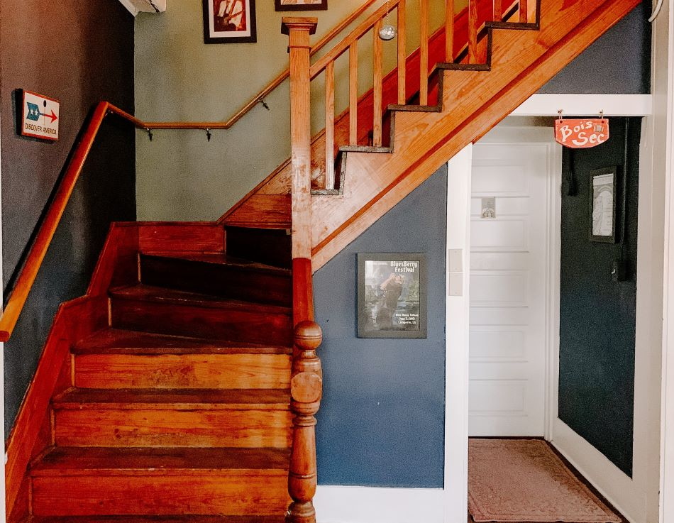 Wooden staircase with dark blue and black walls, framed pictures above, and signs on the walls