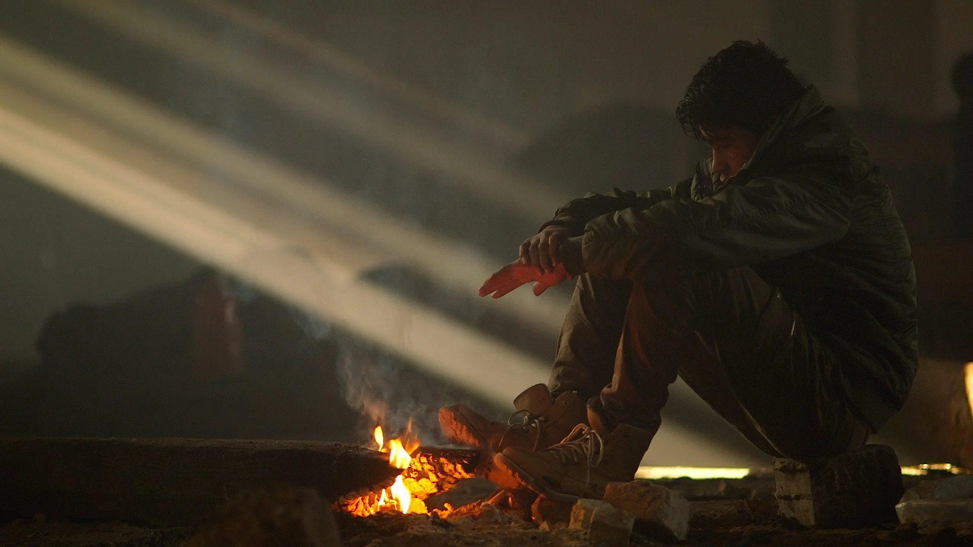 A boy sits by a fire in the squat in Belgrade, Serbia (January 2017)