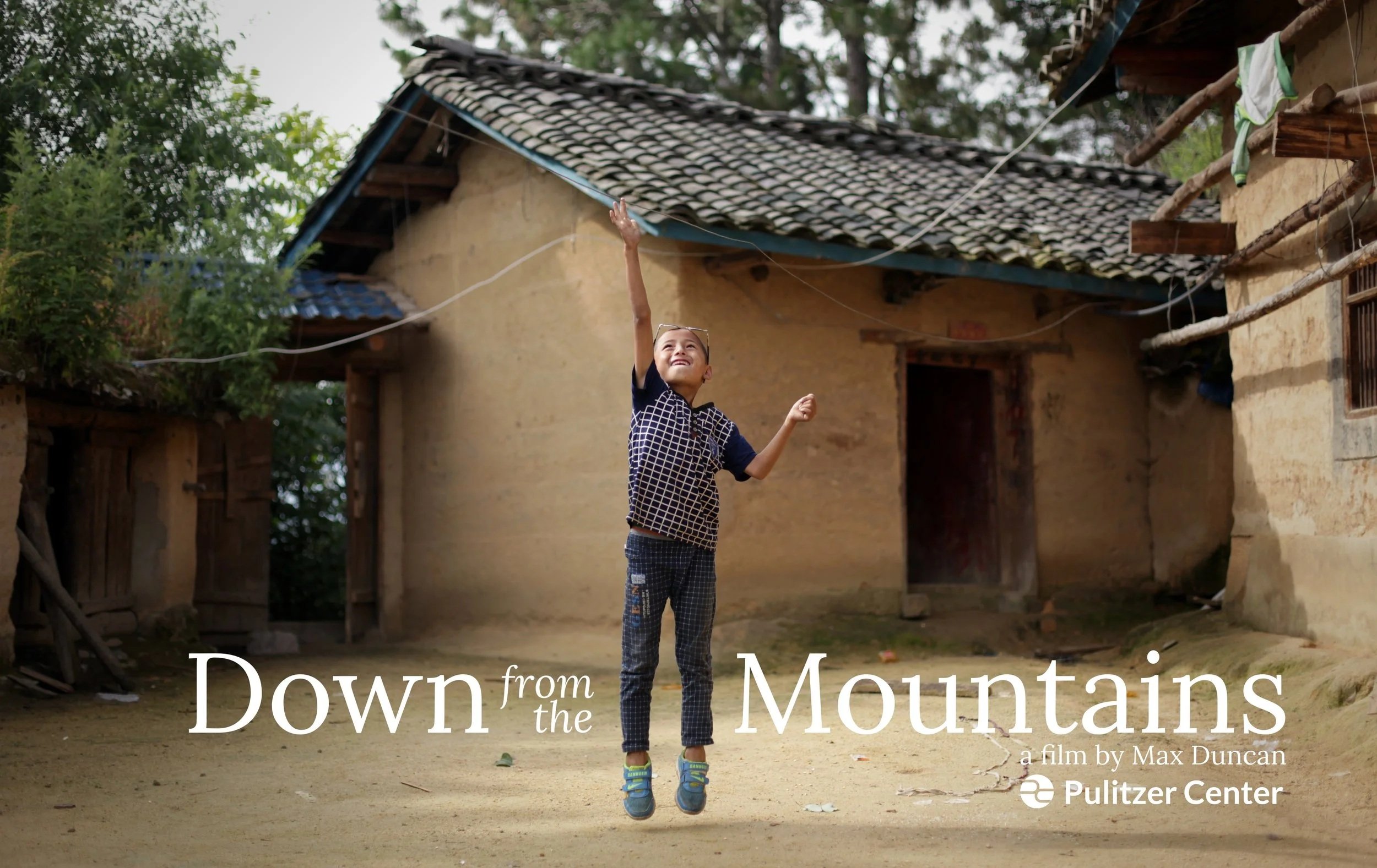 A young boy jumps in the air, reaching for a string tied to a kite, in a rural village with traditional clay houses in the background. The image features the title 'Down from the Mountains' by Max Duncan, with the Pulitzer Center logo.