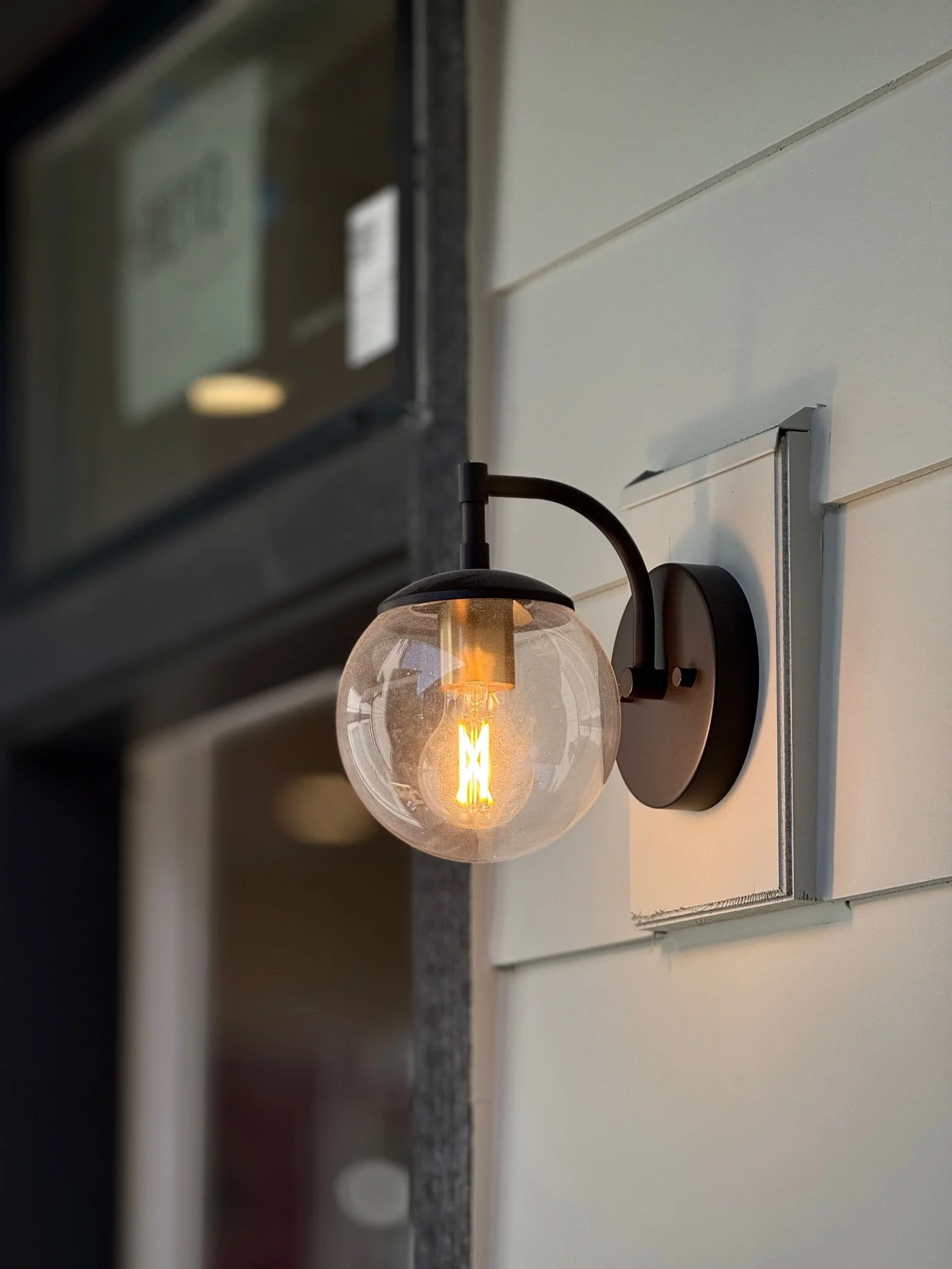 Exterior wall-mounted light fixture with a round clear glass globe and visible filament bulb.