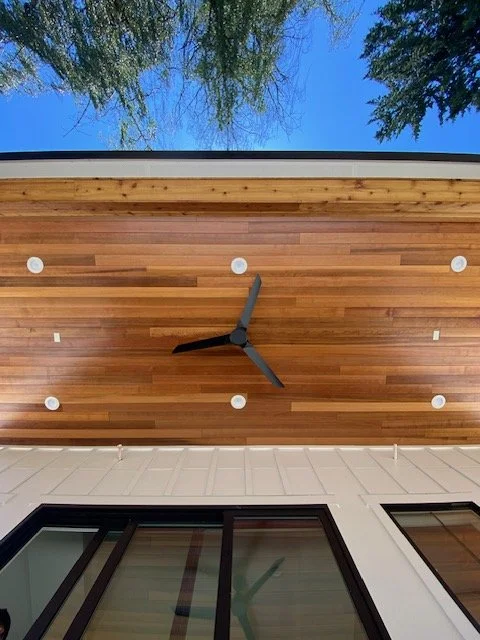 Exterior view of a modern house with a wooden overhang clock and windows