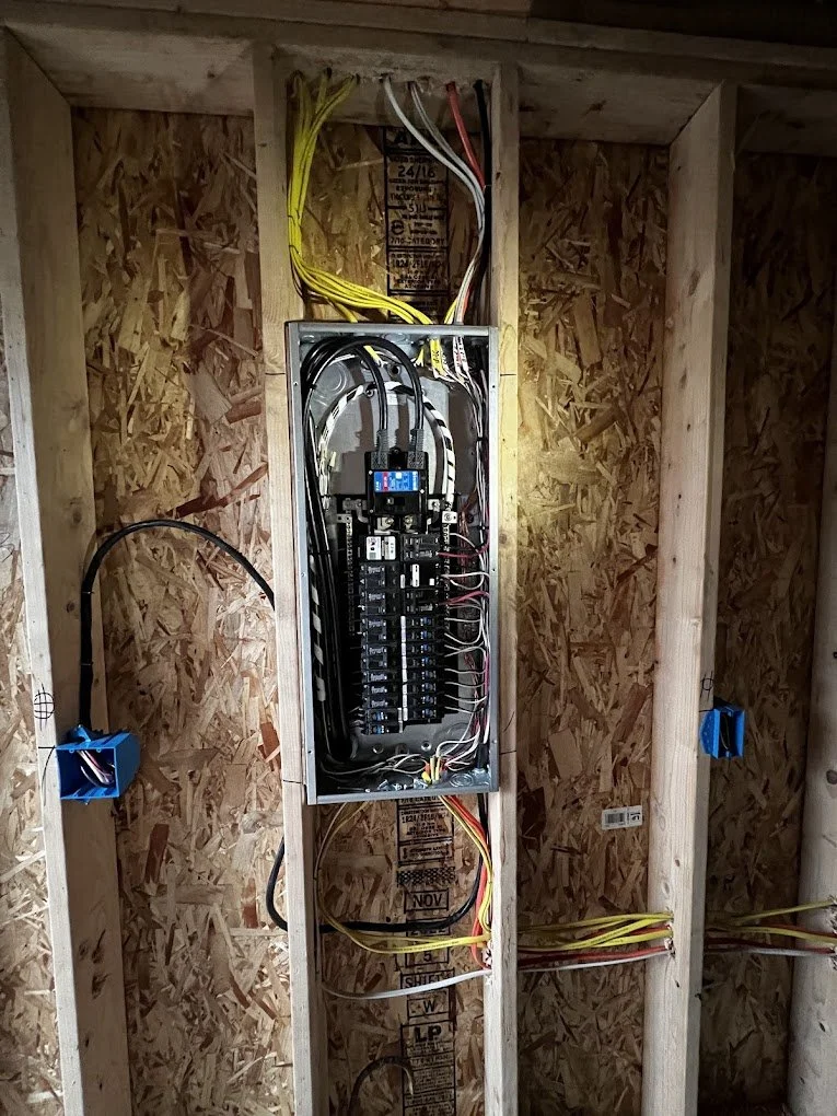 Electrical breaker box with various wires installed inside a wooden wall.