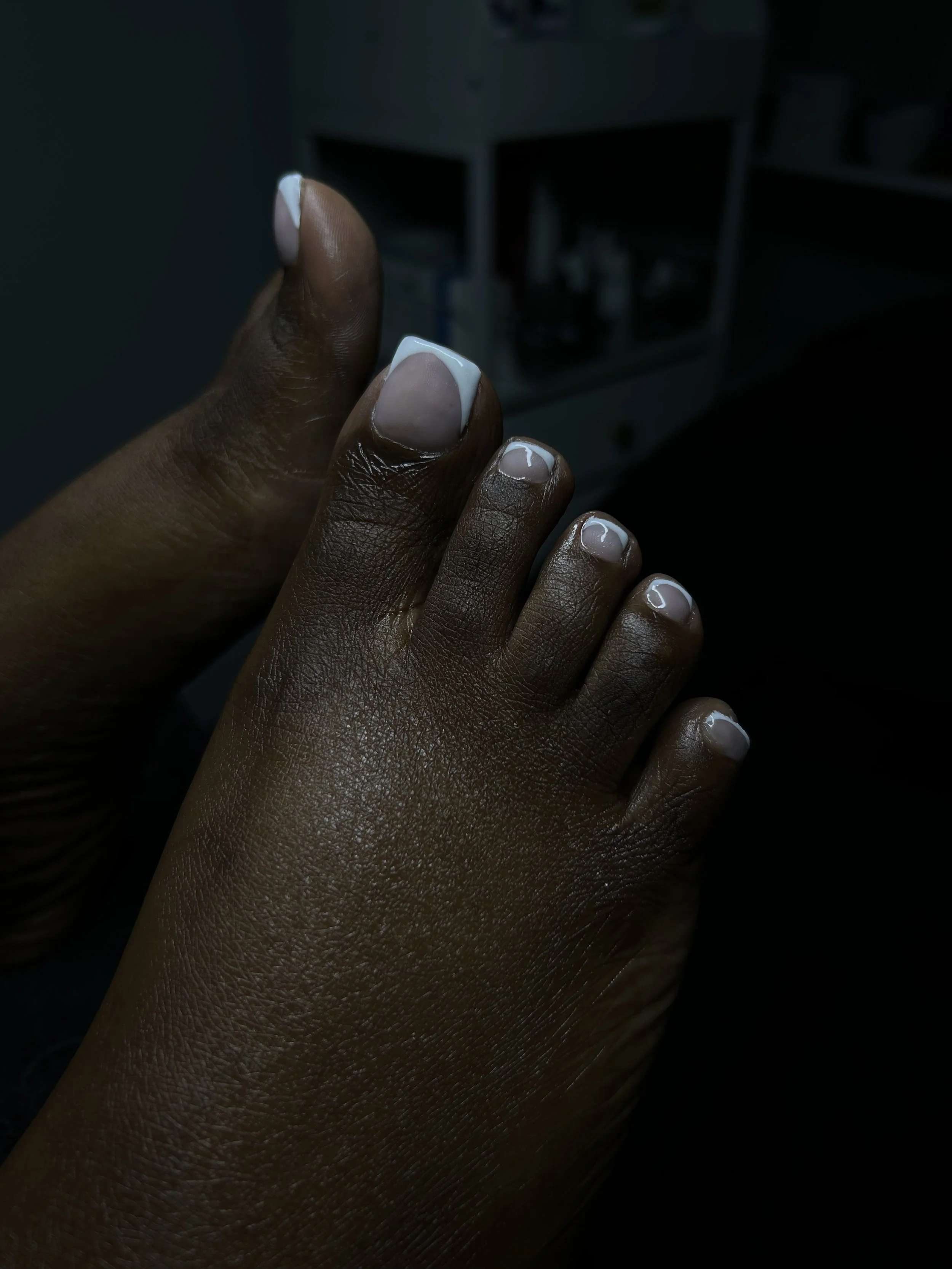 Close-up of a person's hand with painted fingernails, showcasing neatly manicured nails with white tips.