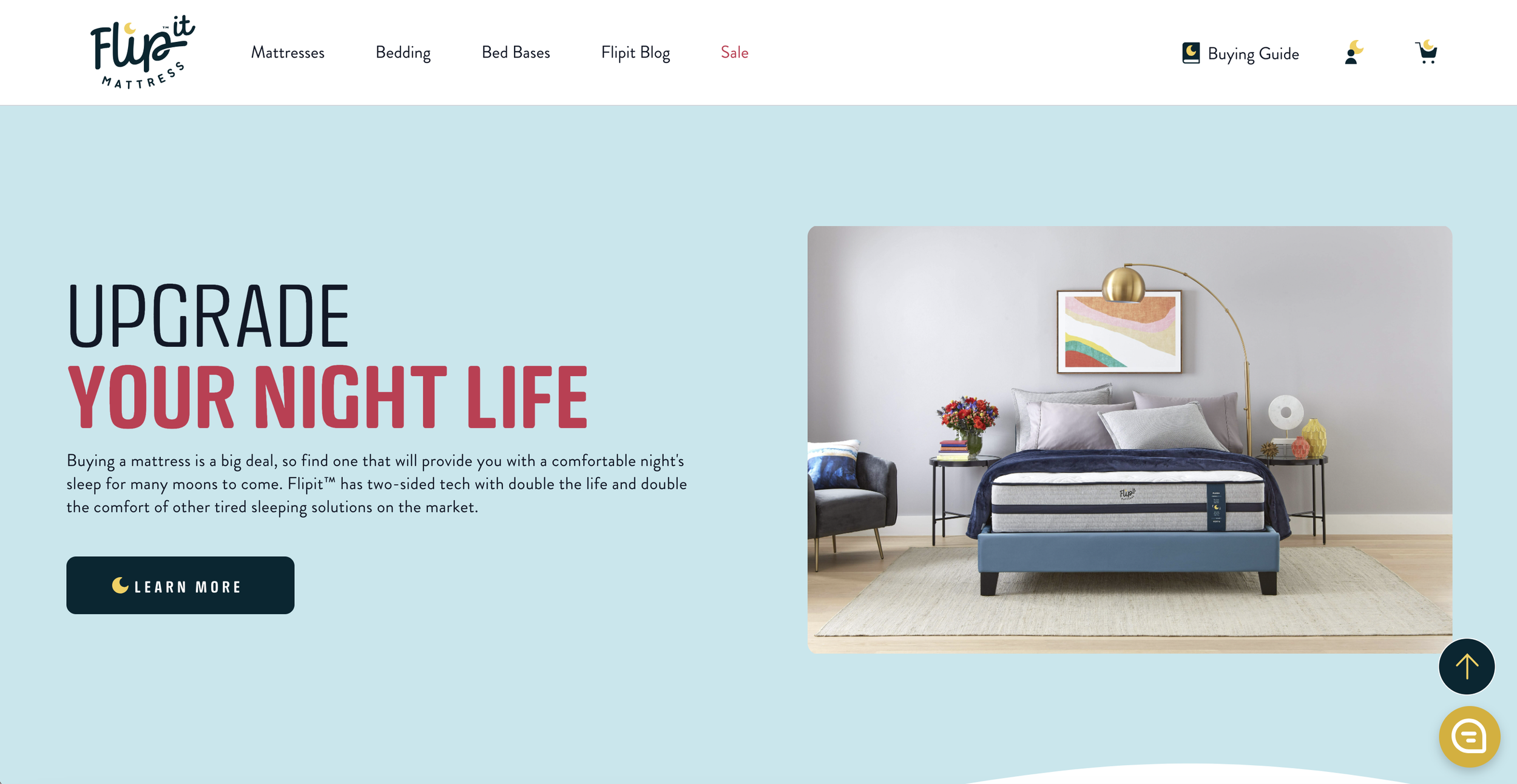 A bedroom with a mattress on a bed frame, a side table with a vase of flowers, and contemporary wall art, with a large blue advertisement section on the left promoting mattress upgrades.