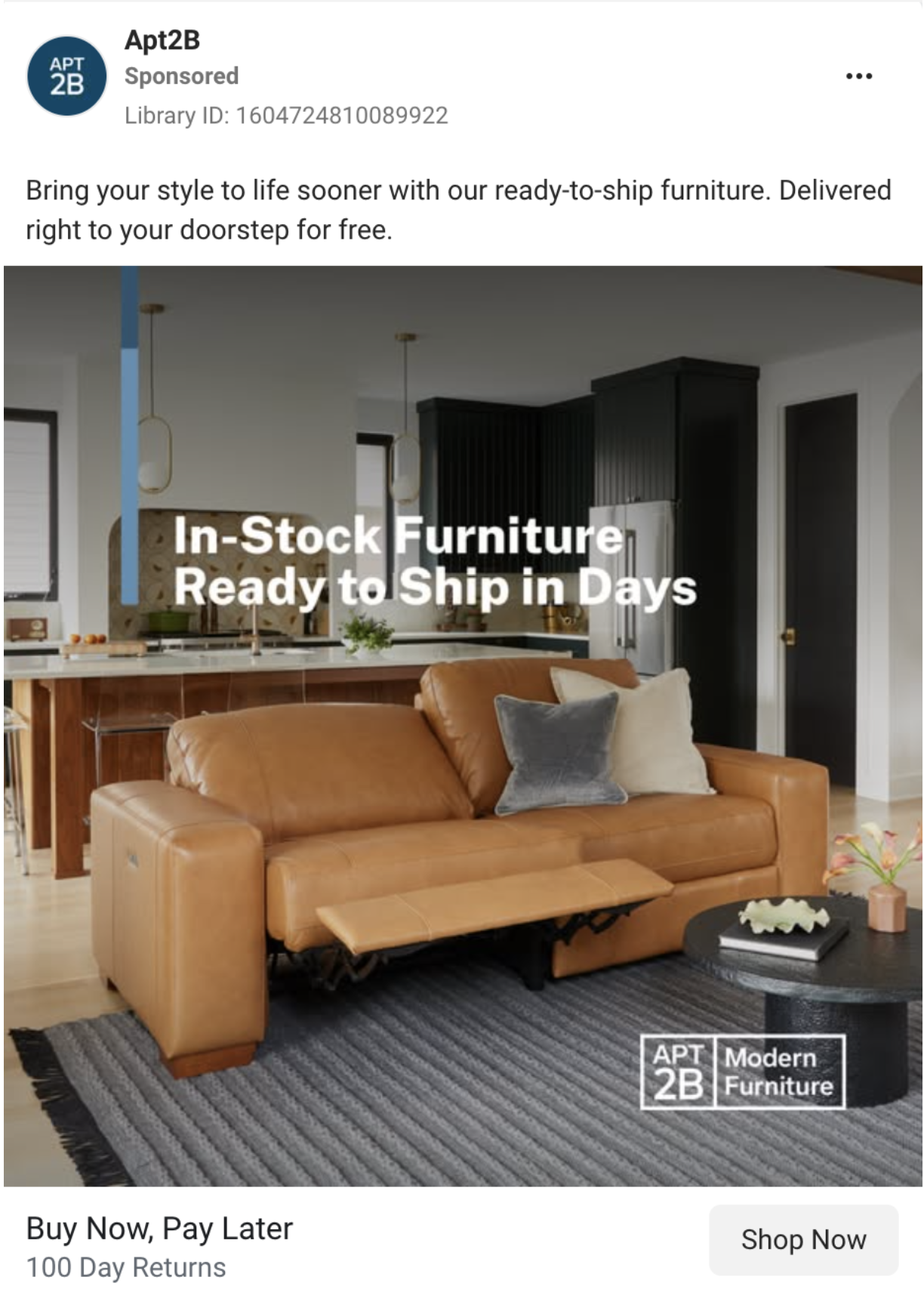 Living room with tan leather sofa, gray accent pillow, black coffee table with a white decorative object, and striped rug. Open kitchen in background with black cabinets, white walls, and pendant lighting. Overlaid text reads "In-Stock Furniture Ready to Ship in Days" and decorator logo in bottom right corner.